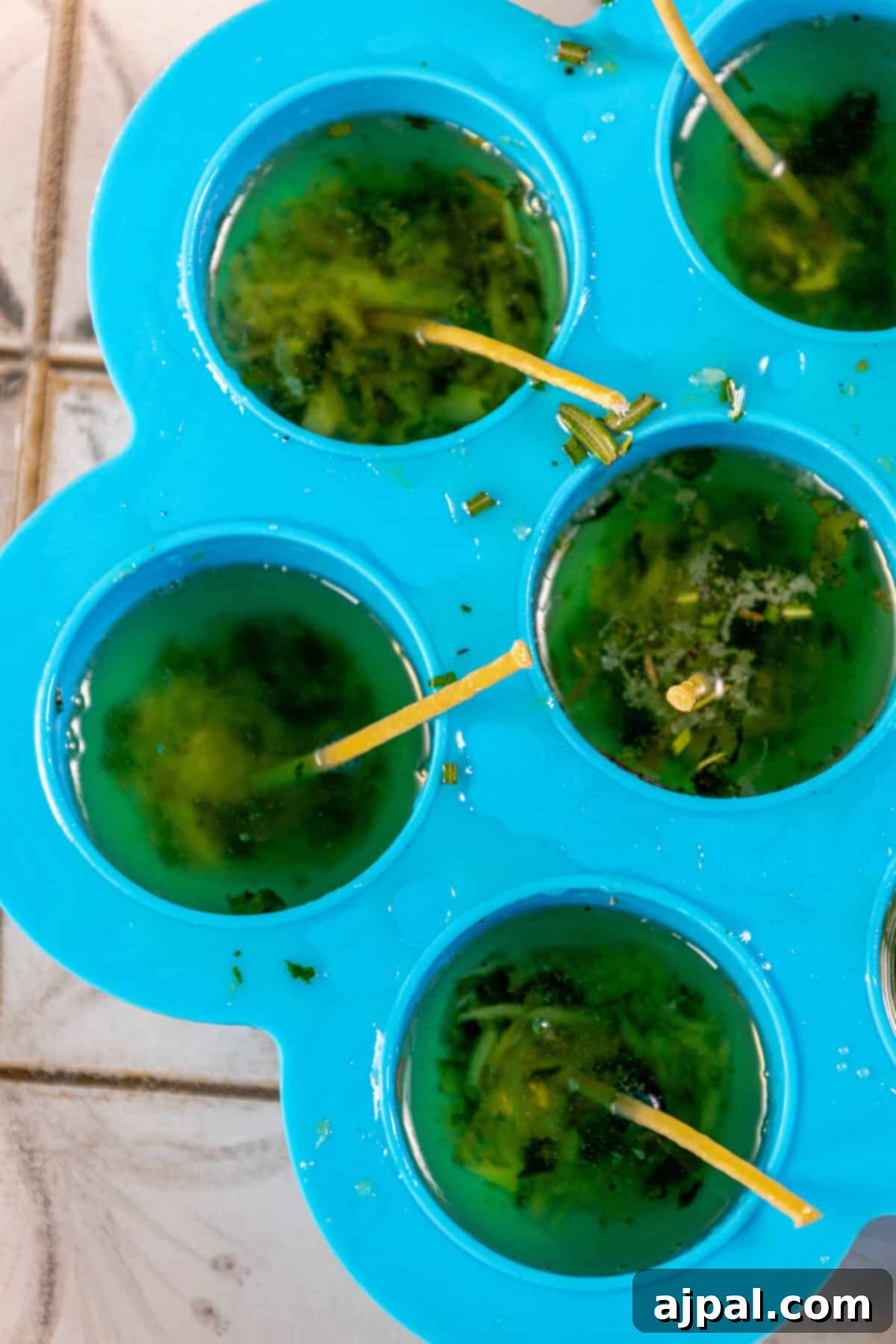 A captivating arrangement of ice cubes filled with a vibrant green liquid, beautifully framed by the flickering glow of tallow candles.