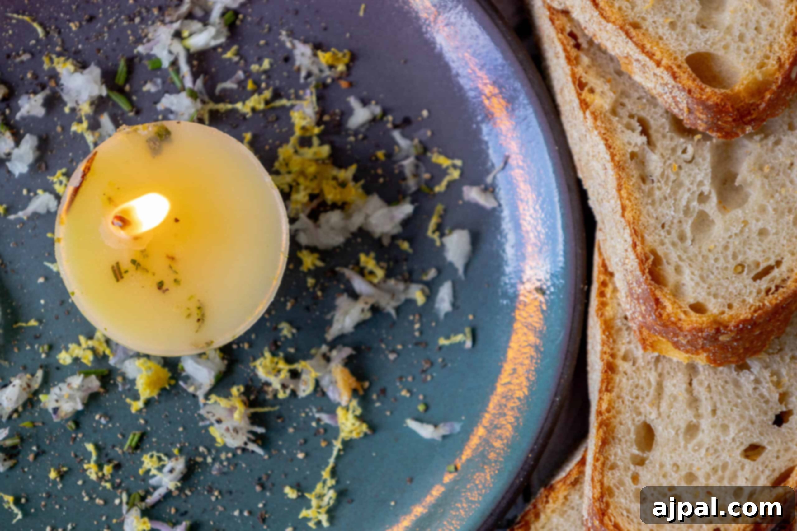 A charming edible tallow candle sits elegantly on a plate with freshly baked bread, inviting guests to dip.