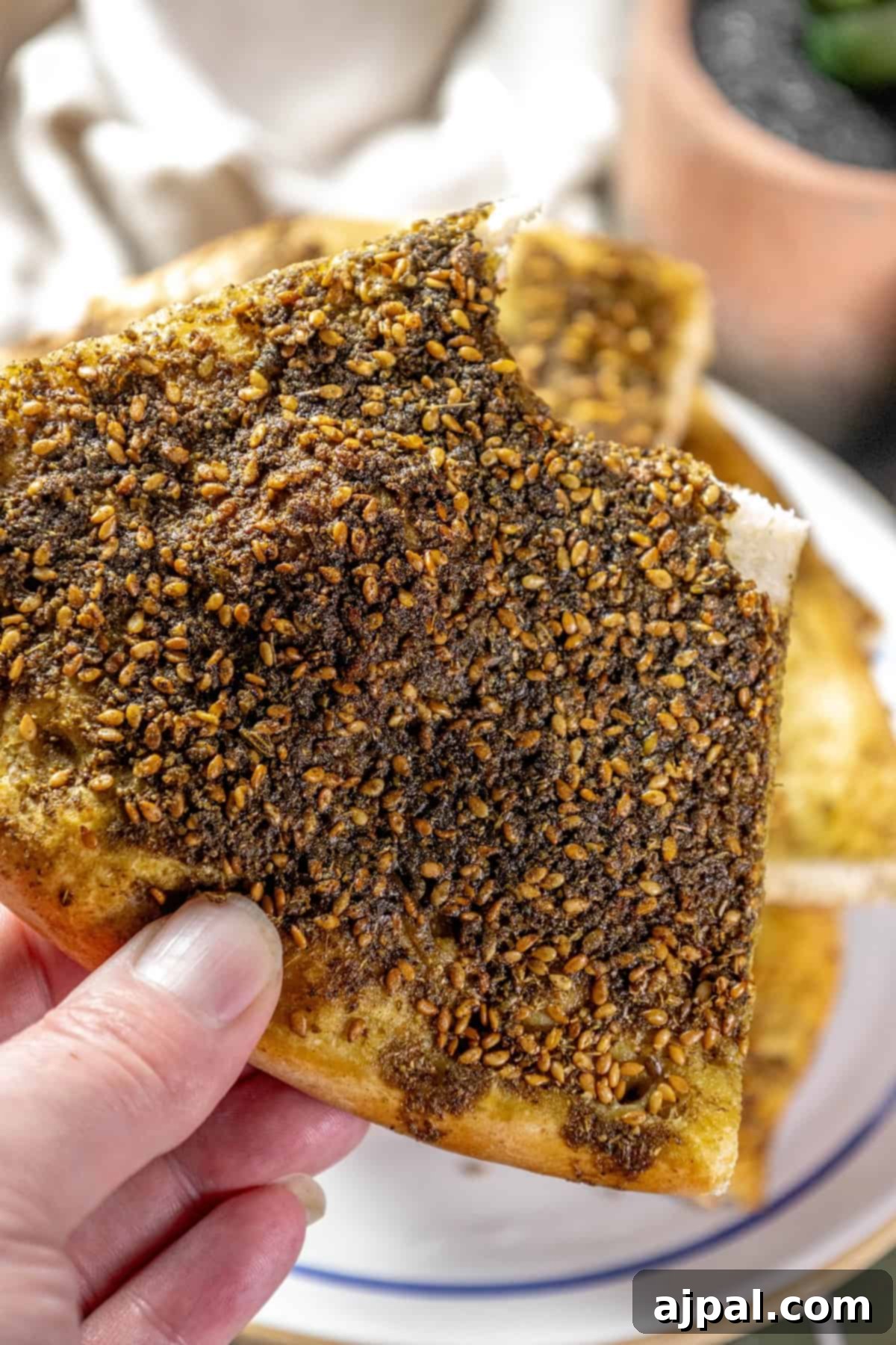 Aromatic Zaatar Pizza 11 A person holding a piece of bread with Za'atar sprinkled on it.