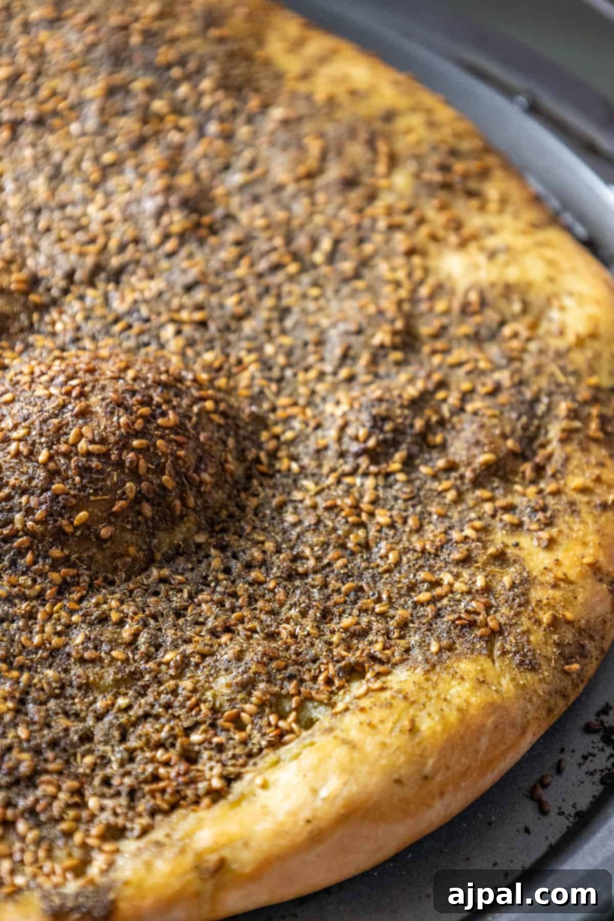 Aromatic Zaatar Pizza 3 A Za'atar pizza, also known as za'atar manakish, is sitting on a pan with seeds on it.