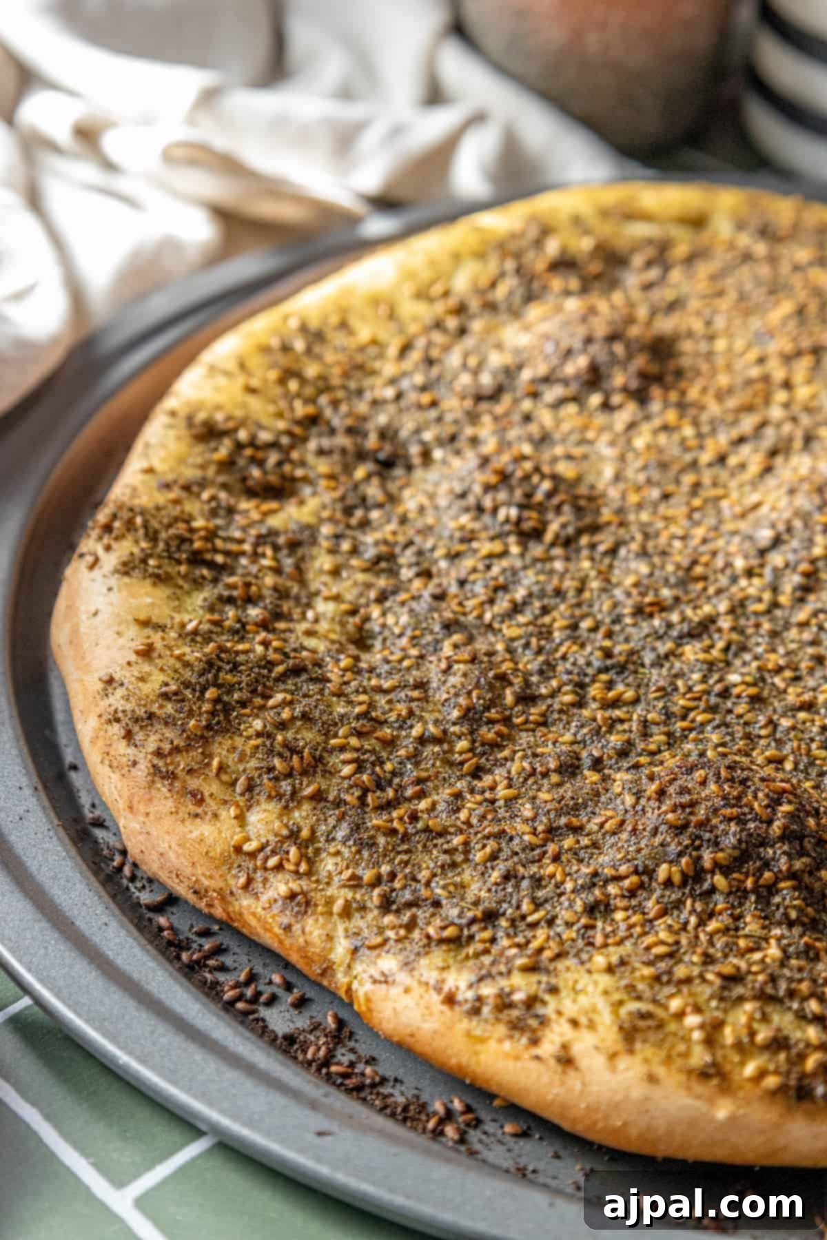 Aromatic Zaatar Pizza 8 A pizza is sitting on a pan with za'atar spices on it.