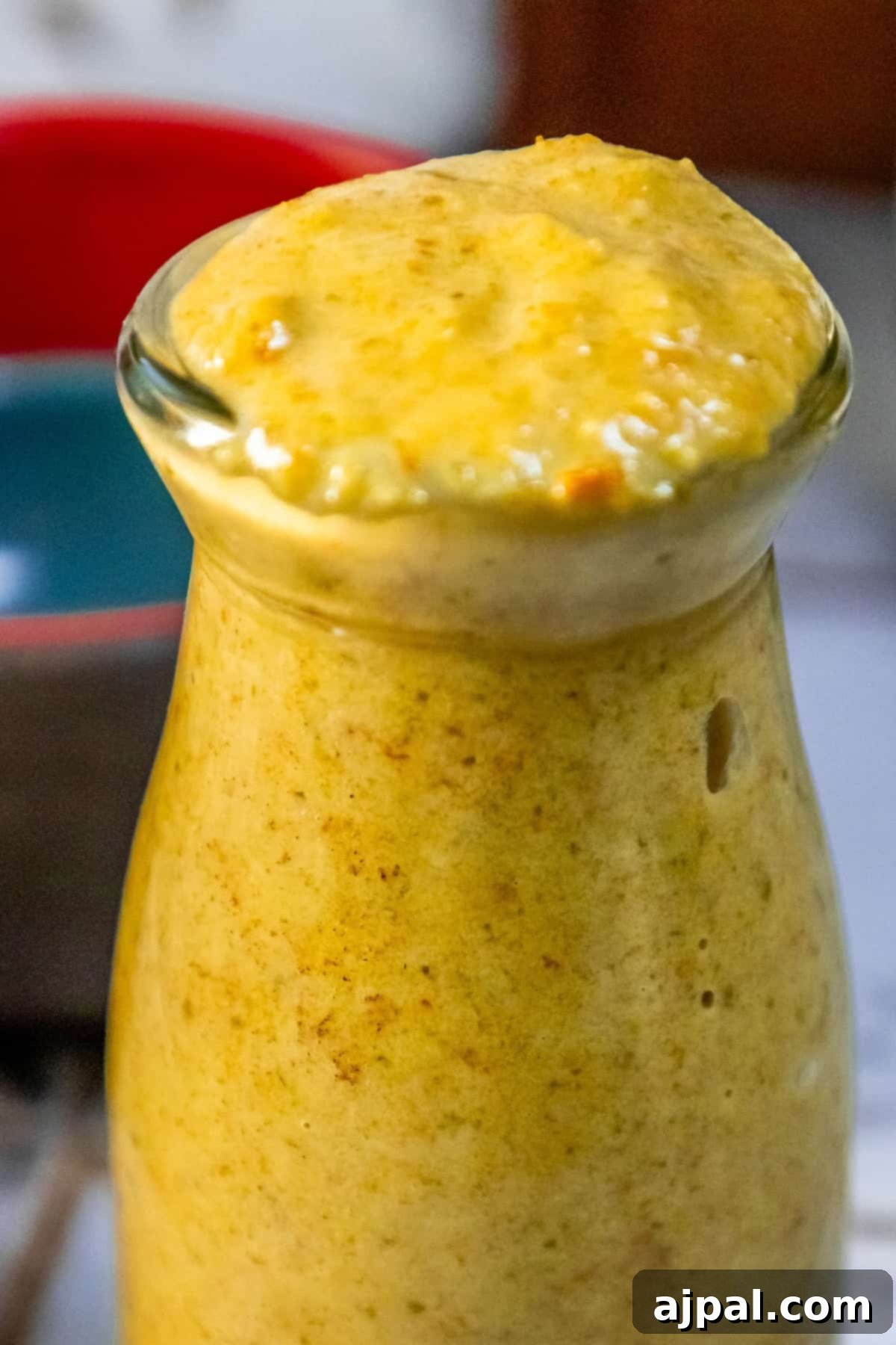 A jar of homemade habanero hot sauce sitting on a rustic wooden table, showcasing its rich, fiery orange hue.