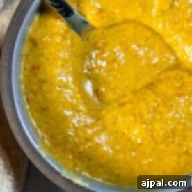 A bowl of soup with a spoon next to it, infused with a hint of spice thanks to the addition of jalapeño.