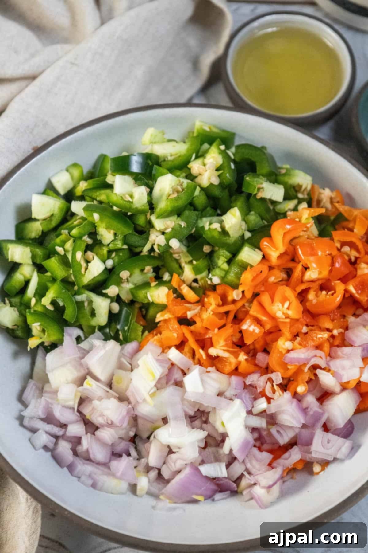 Chopped habaneros, jalapeños, garlic, and shallots in a bowl, prepared for cooking.