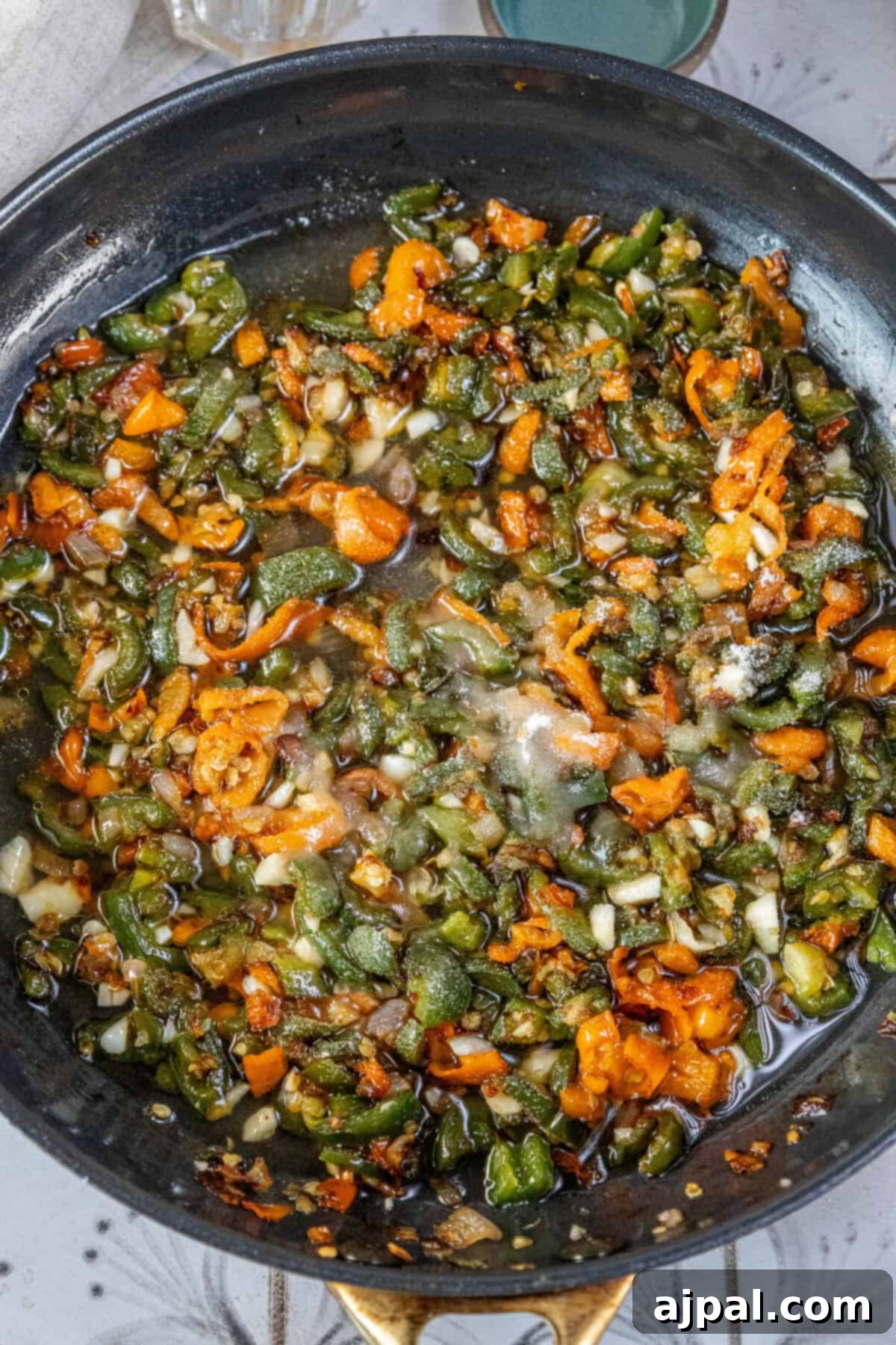 A fiery frying pan sizzling with peppers and other vegetables, beautifully caramelized, infused with the essence of hot sauce.