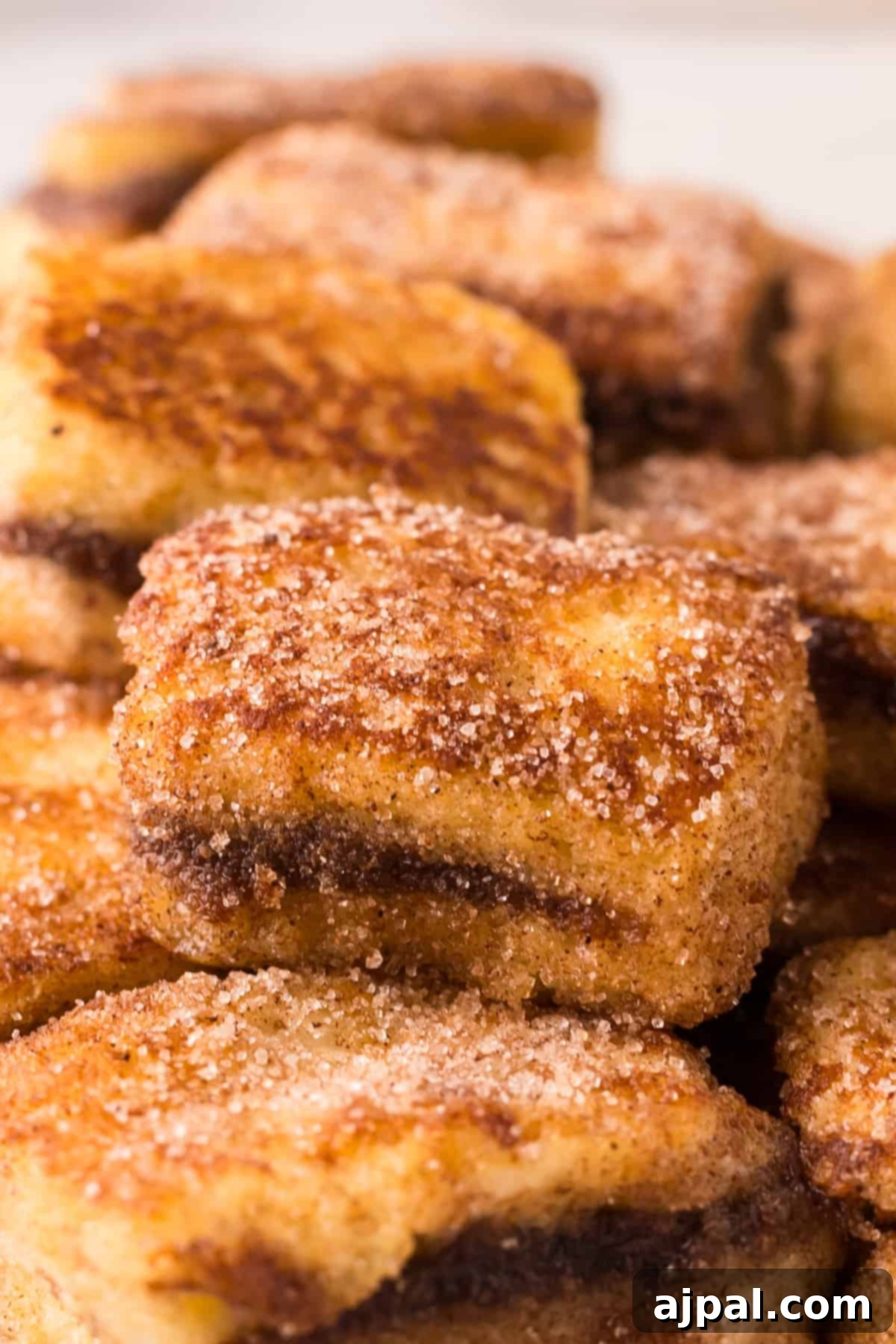 A stack of cinnamon sugar Nutella Stuffed French Toast Bites, glistening with syrup.