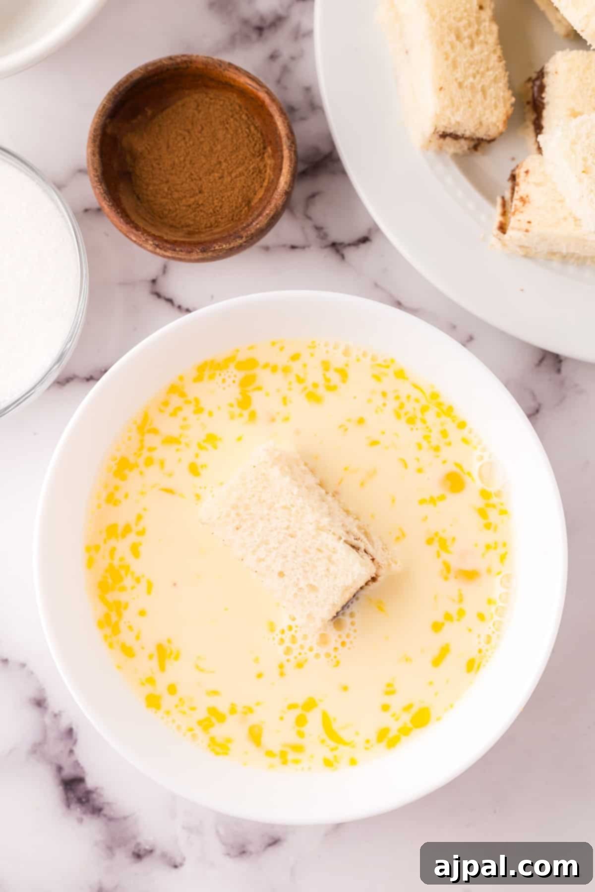 A shallow bowl of egg and milk mixture, ready for dipping French toast.