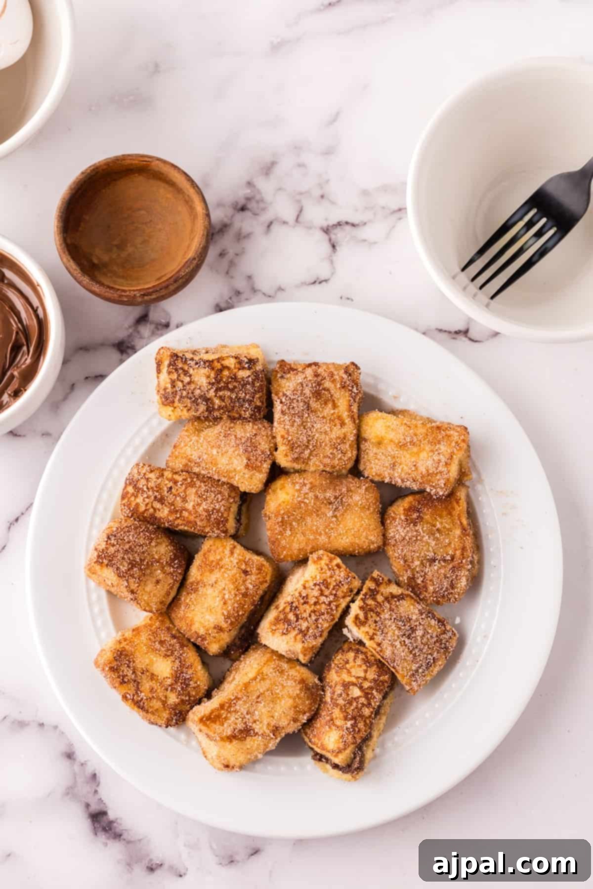 Cooked Nutella Stuffed French Toast Bites on a marble surface, ready to be coated with cinnamon sugar.