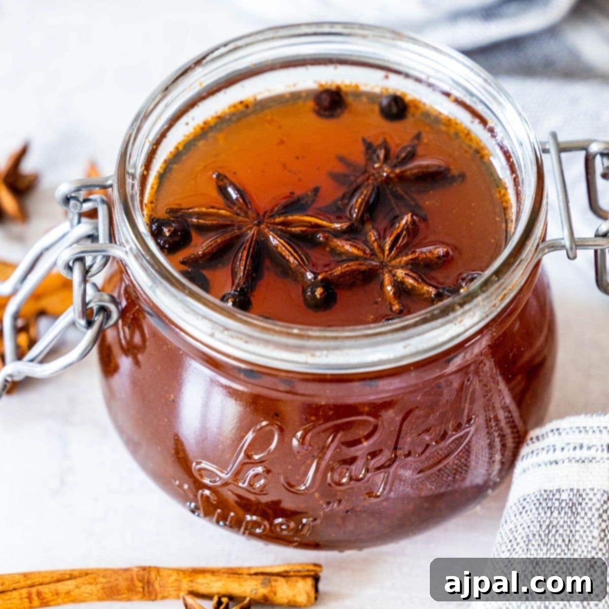 picture of mulled simple syrup in a jar with star anise and juniper berries floating on top