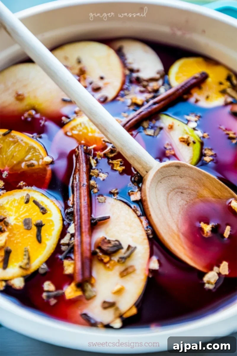 Non-alcoholic spiced ginger wassail with cinnamon sticks and orange slices in a bowl.