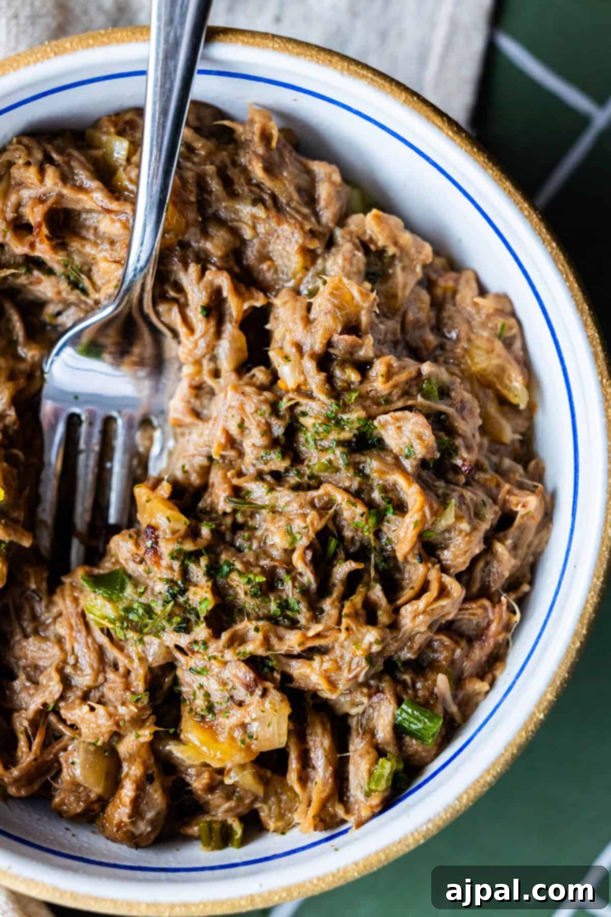 Bowl of shredded beef mixed with vegetables and herbs, inspired by Onion Soup Pot Roast.