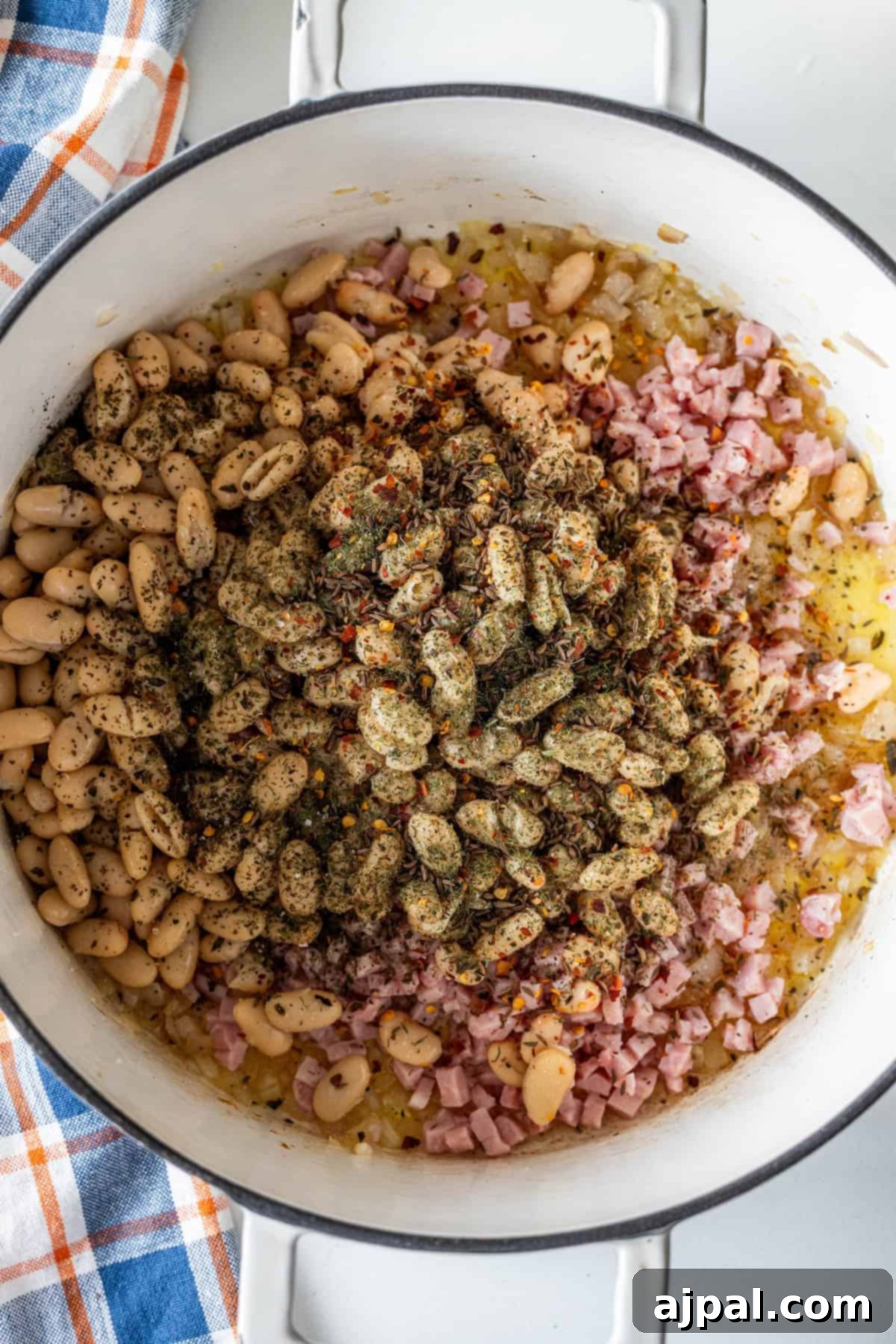 Pot of white beans, ham, onions, herbs, and spices