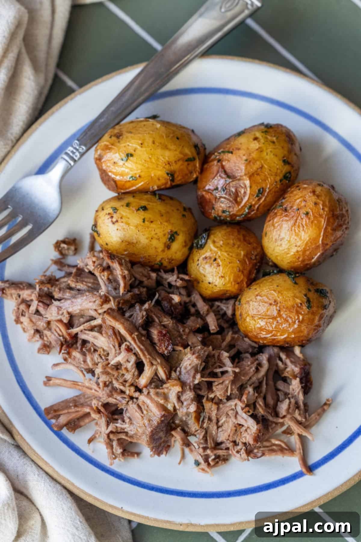Slow Cooker Chuck Roast and roasted baby potatoes on a green tiled surface