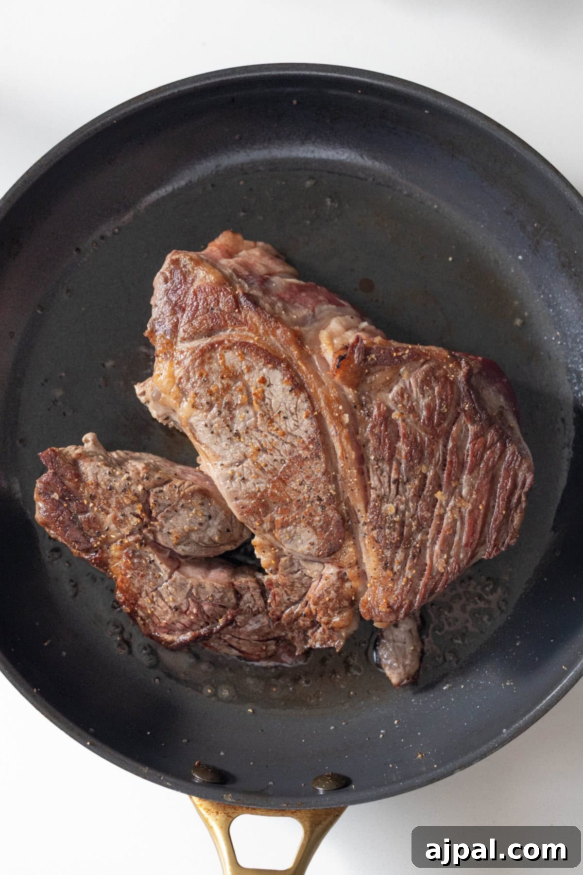 Cooked steak with a browned exterior in a frying pan