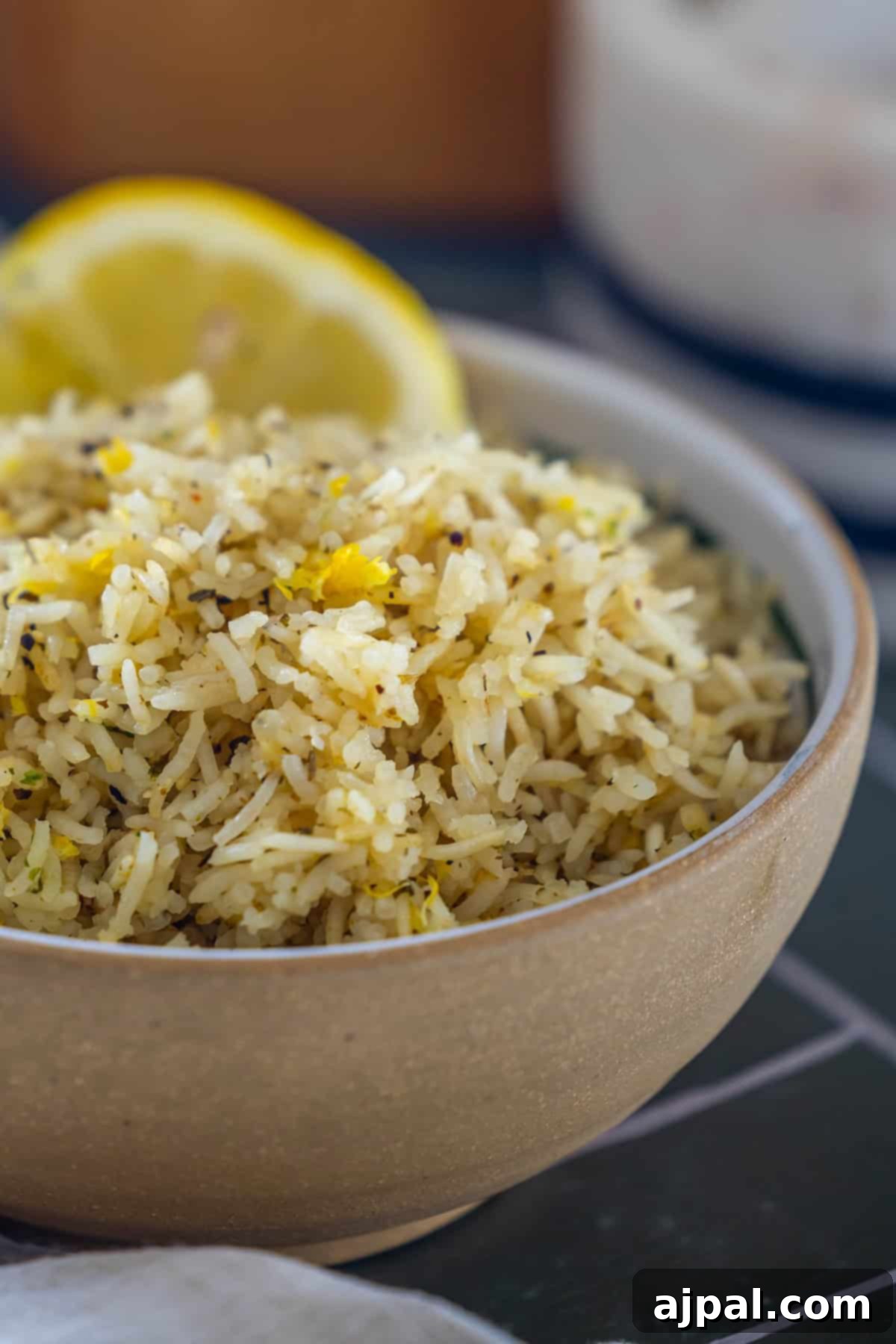 A bowl of baked lemon rice seasoned with pepper and a lemon slice.