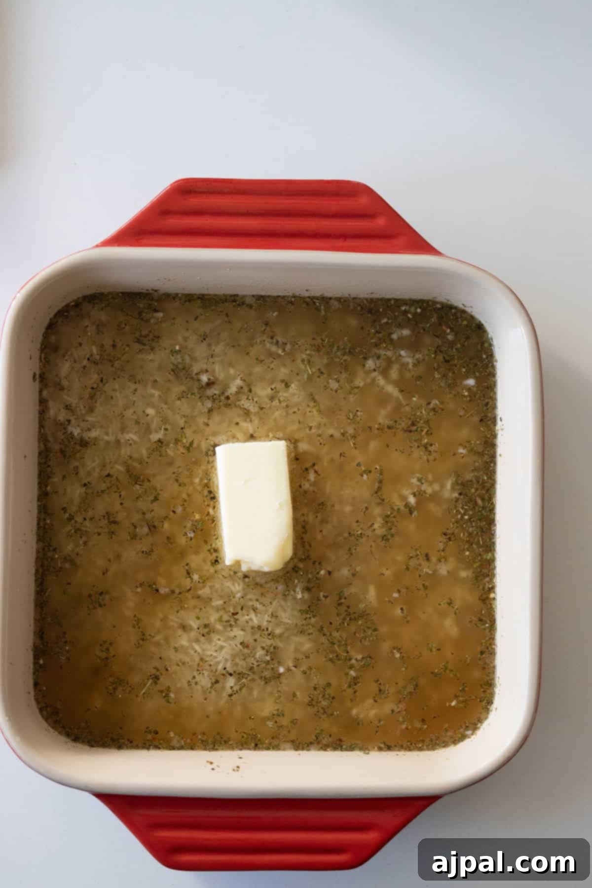 Rice, stock, and butter in a baking dish.