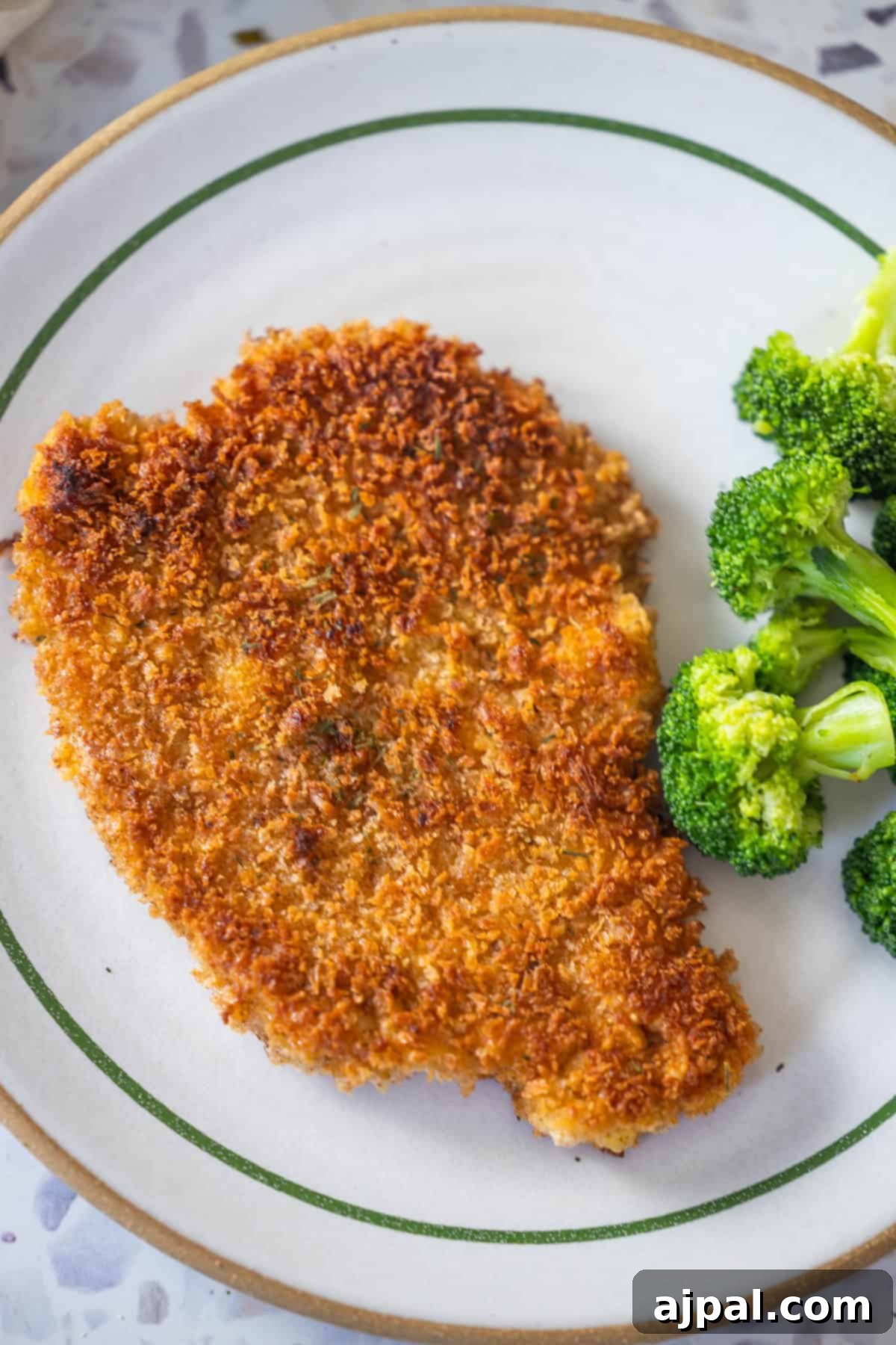 Pork Schnitzel: A Crispy, Golden Delight 4 A crispy Pork Schnitzel is served on a plate alongside steamed broccoli florets—an easy and satisfying Pork Schnitzel recipe for any meal.