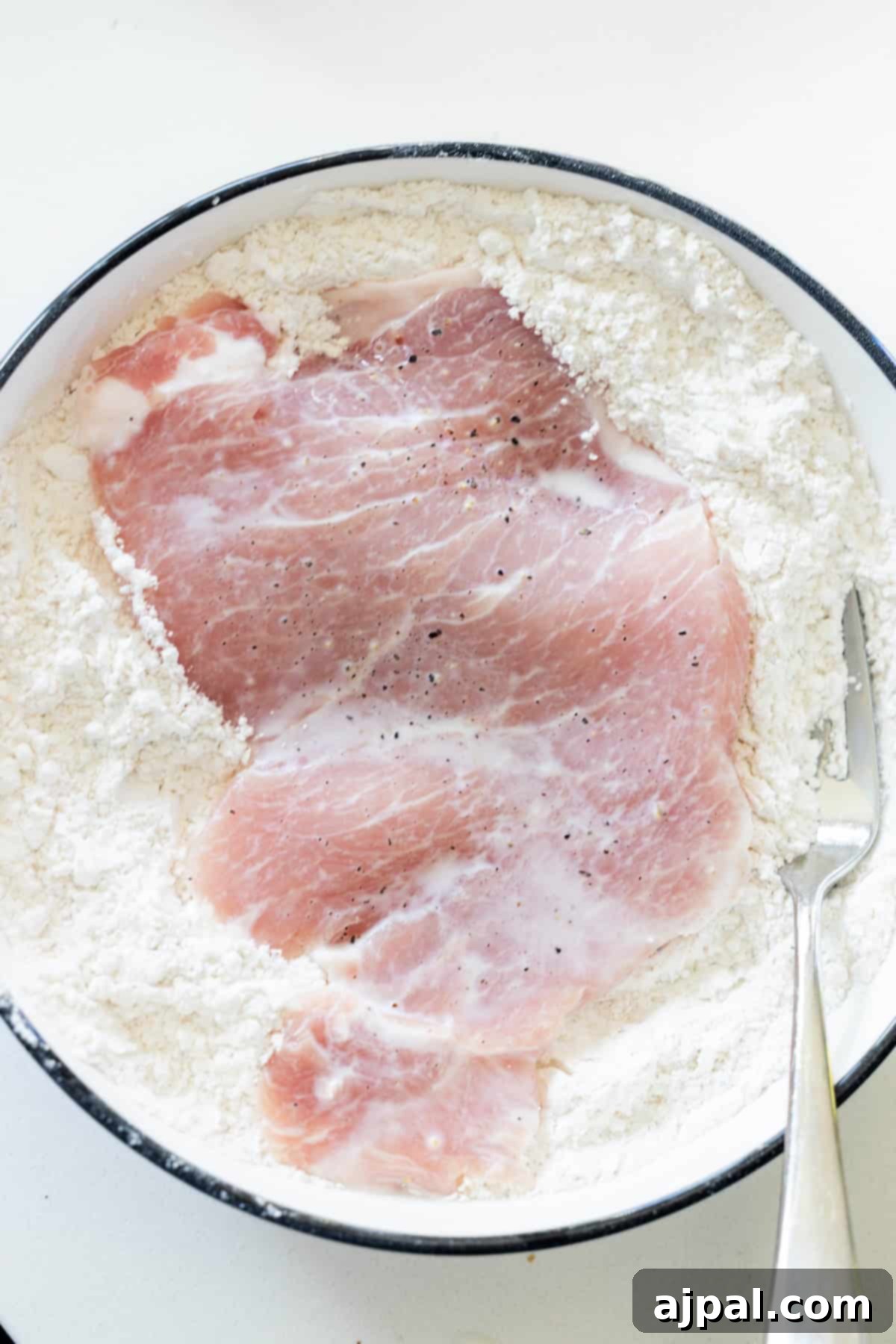 A bowl of food with a spoon, featuring a delicious Pork Schnitzel recipe.