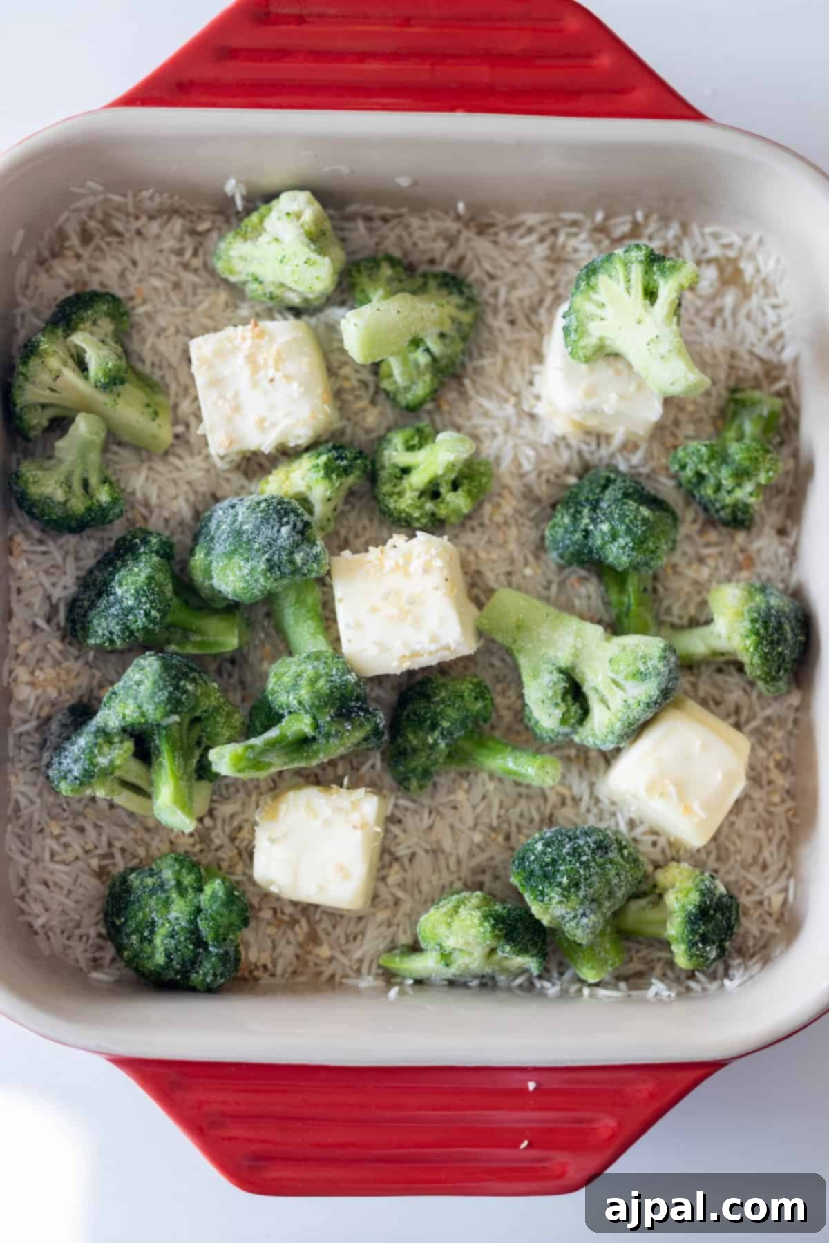 Uncooked rice, broccoli, and butter in a baking dish
