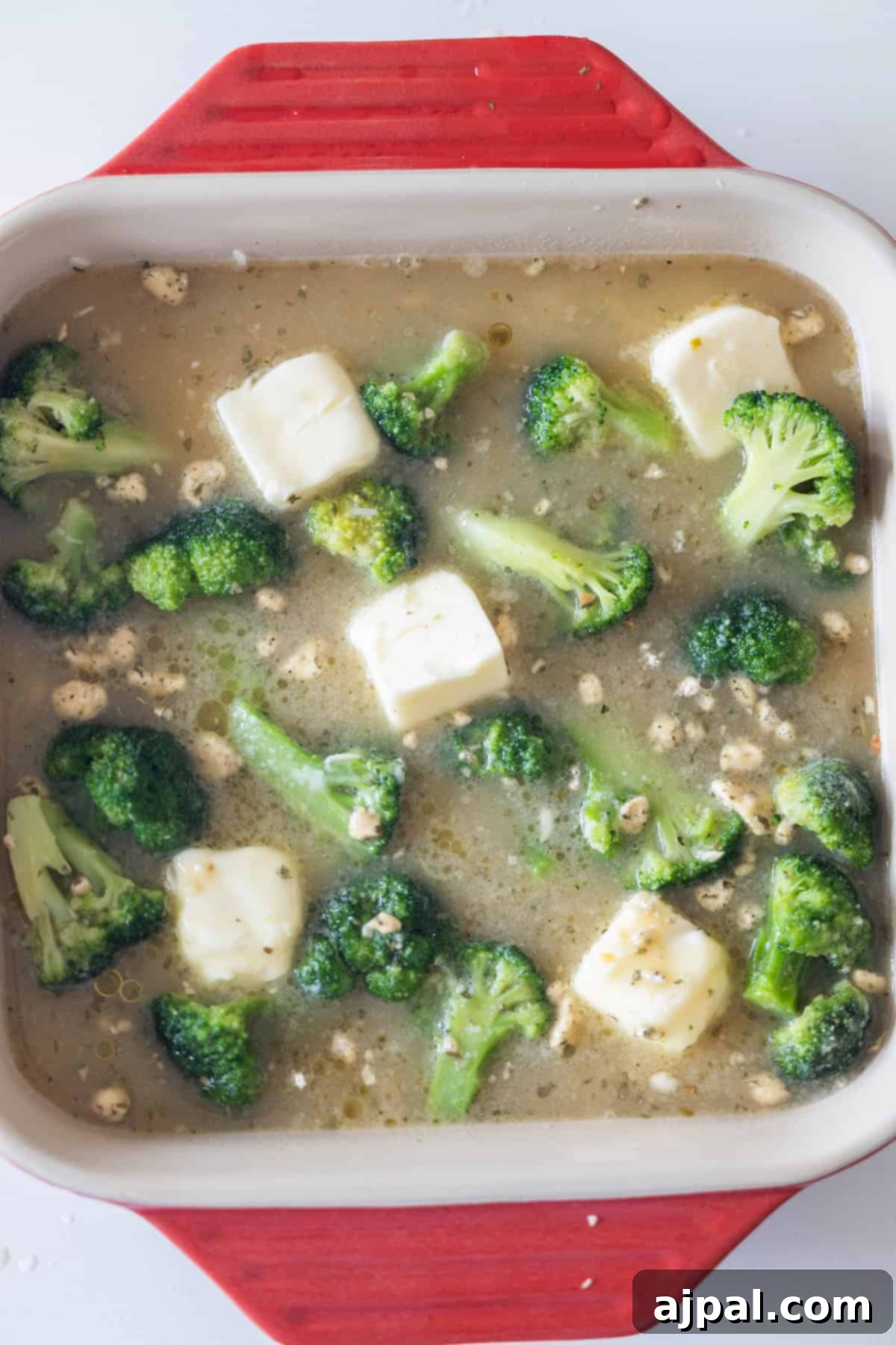Baking dish with rice, broccoli, and broth ready to bake
