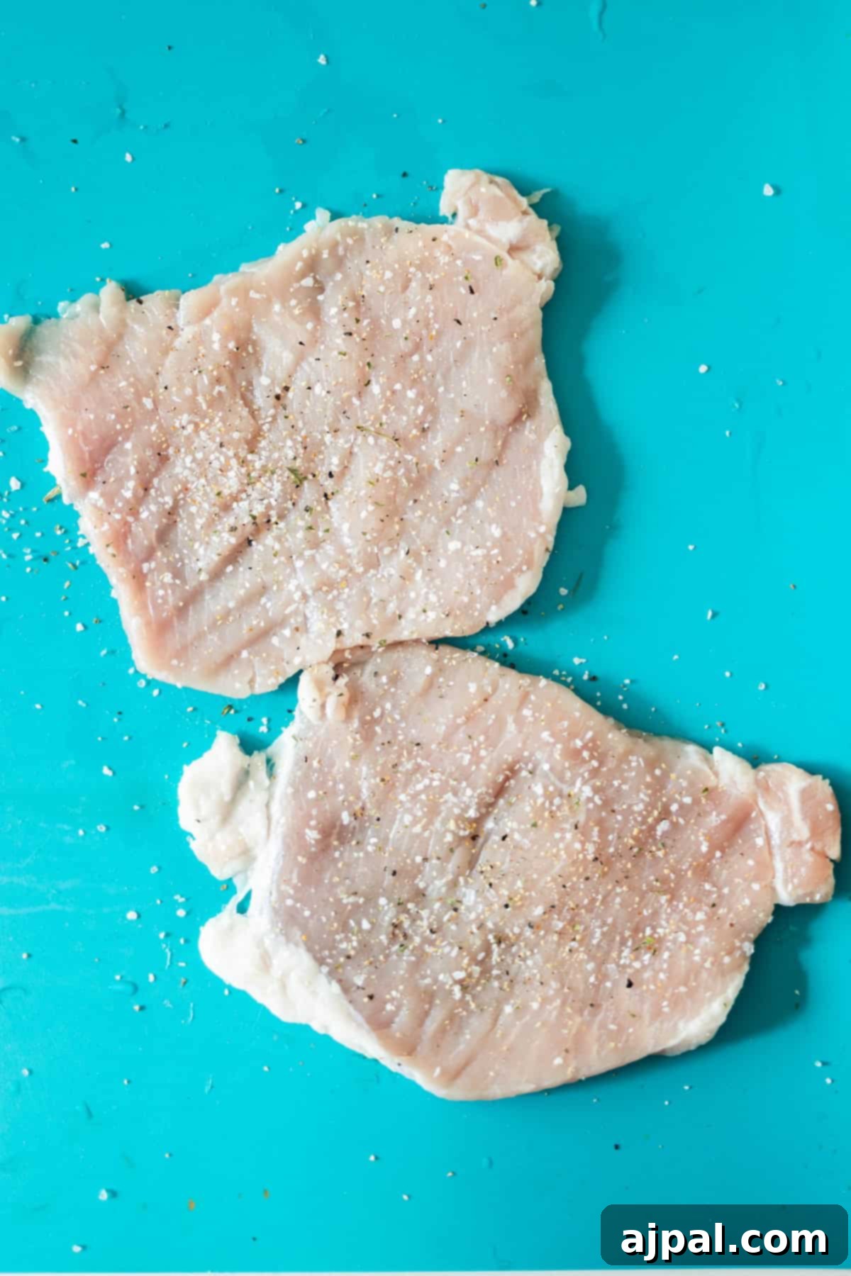 Seasoned pork chops on a cutting board