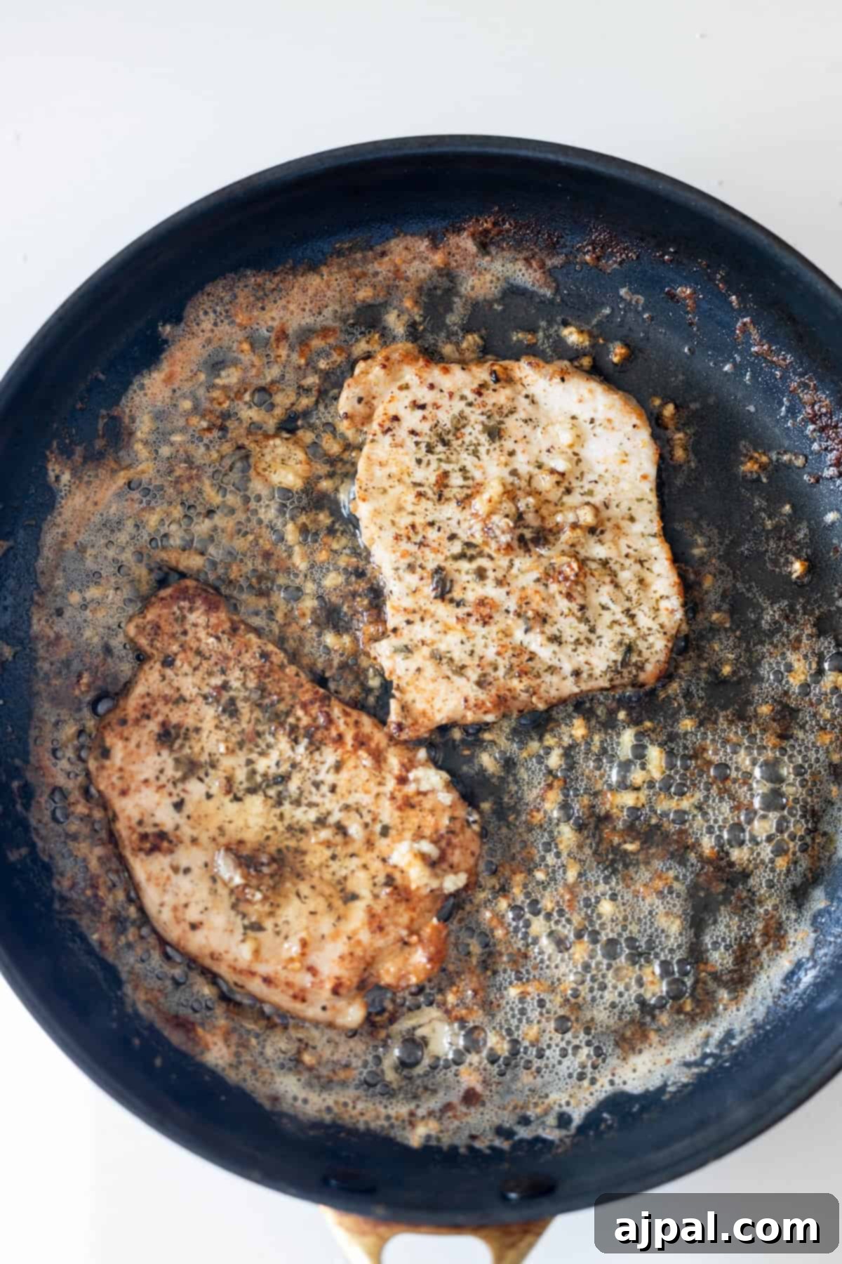 Seasoned chicken breasts cooking in a skillet