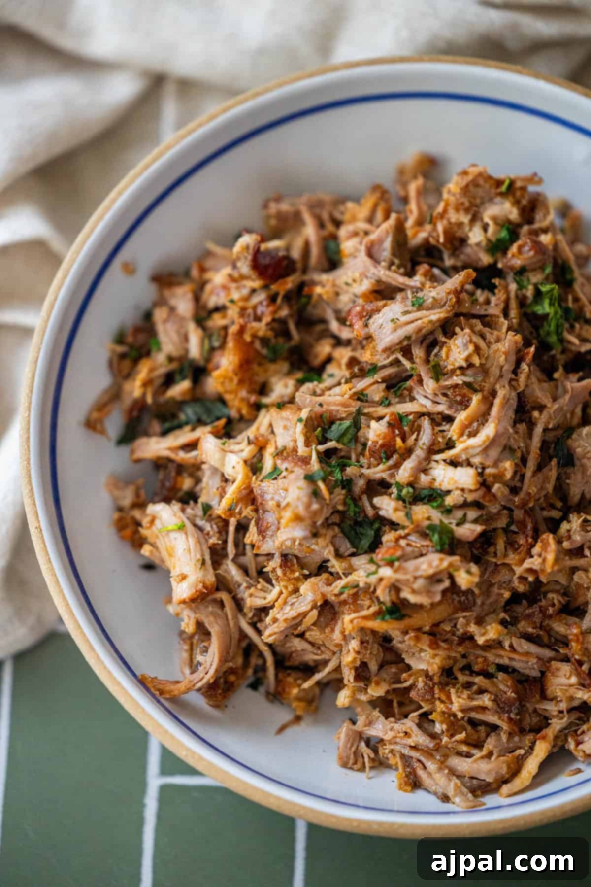 Piri Piri Spiced Country Ribs 3 Bowl of shredded, cooked Country Style Ribs with herbs on a tiled green surface.