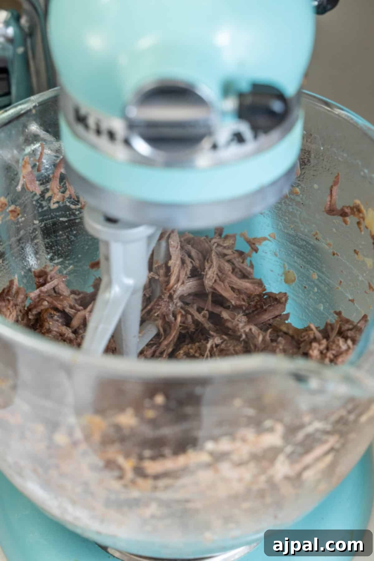 Stand mixer mixing shredded Piri Piri meat.
