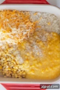 A casserole dish containing shredded cheese, shredded hash browns, creamed corn, whole corn, and breadcrumbs is shown before mixing—perfect for a baked cheesy corn rice casserole.