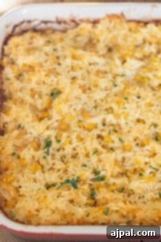 A Cheesy Corn Rice Casserole featuring a golden-brown rice and corn mixture, topped with chopped green herbs, makes for a comforting baked casserole dish.