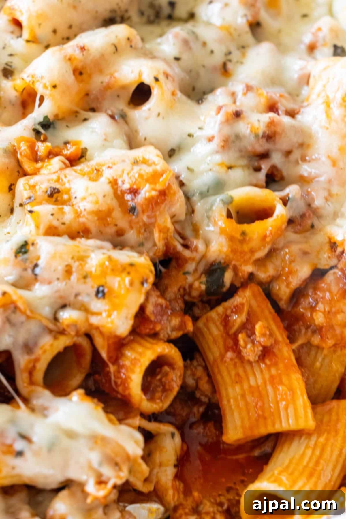Close-up of Cheesy Baked Rigatoni with melted cheese, rich tomato sauce, flavorful ground meat, and fresh herbs