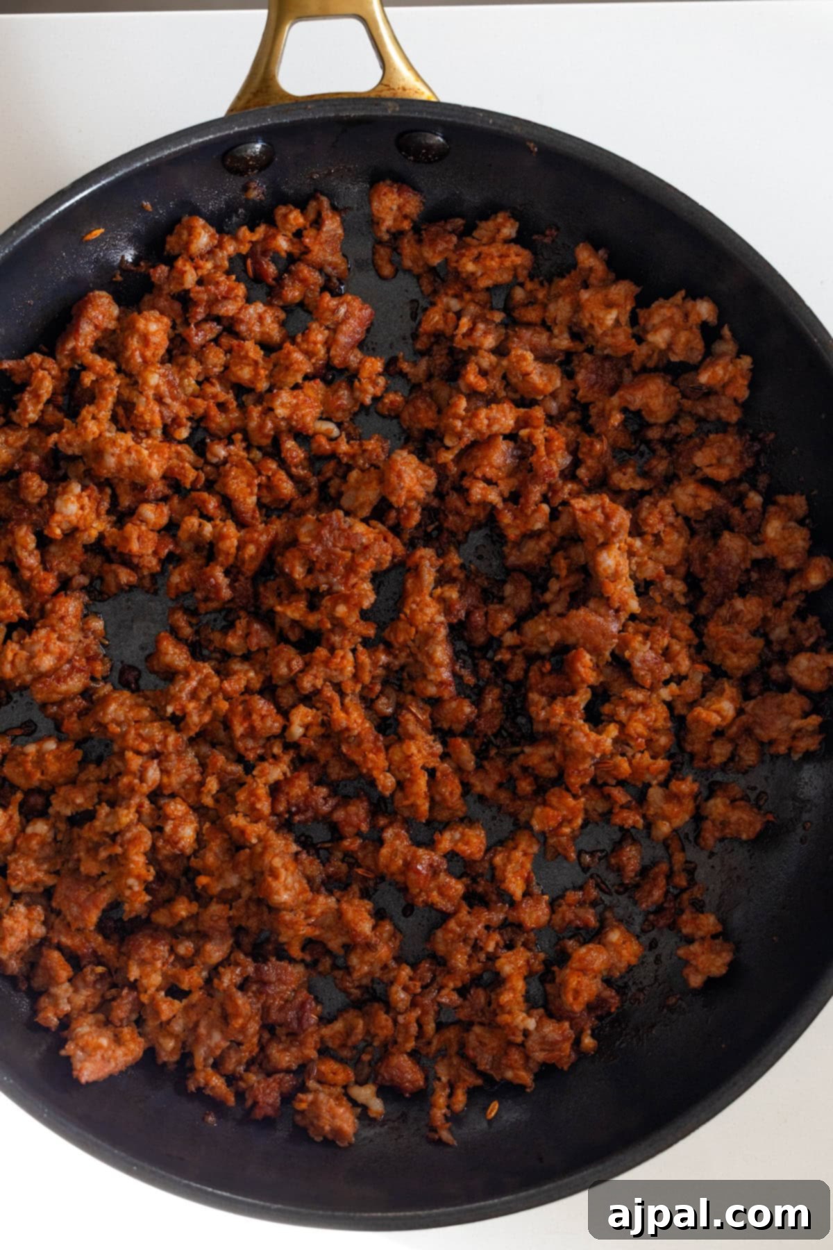 Cooked, crumbled seasoned ground meat in a black skillet