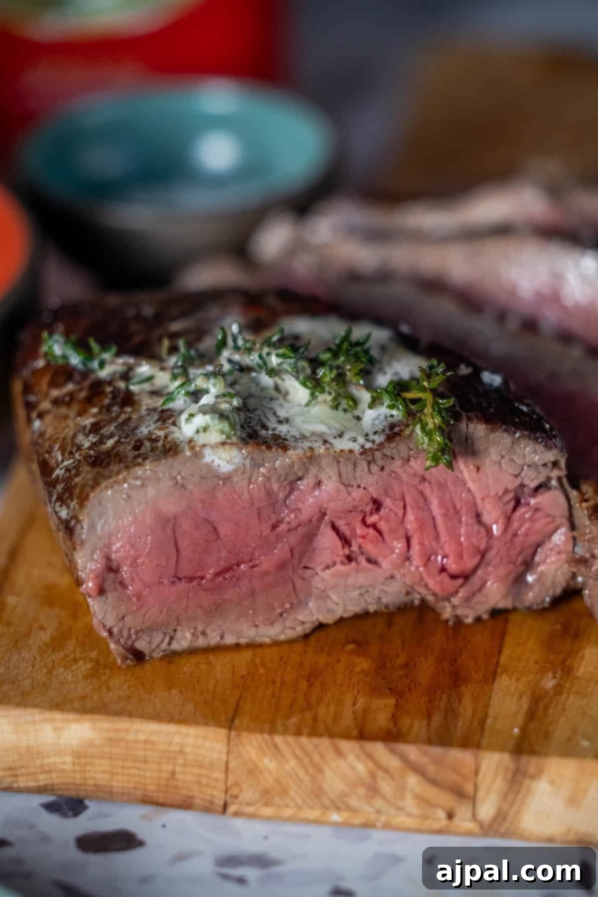 Thick slice of medium-rare sirloin steak with herbs and butter.