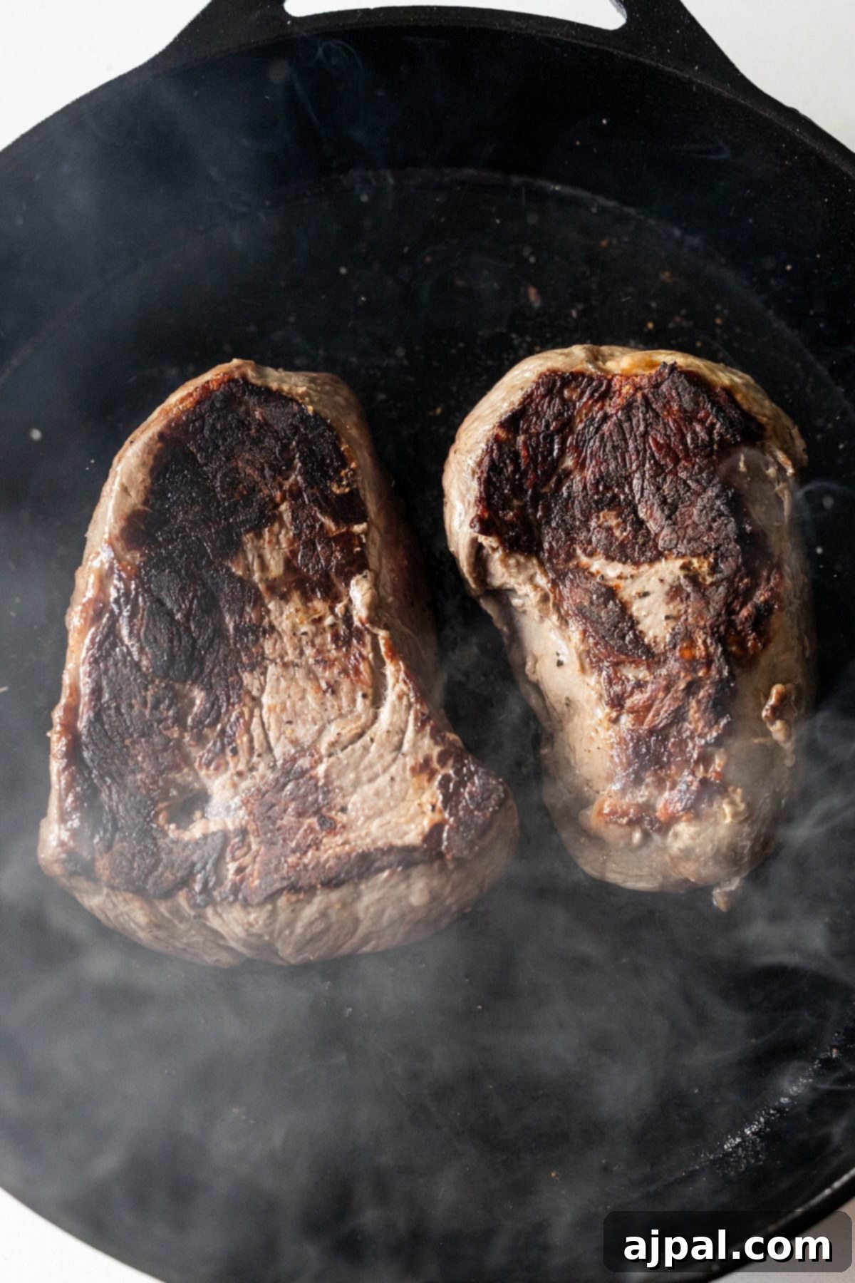 Sirloin steak searing in a cast iron skillet.