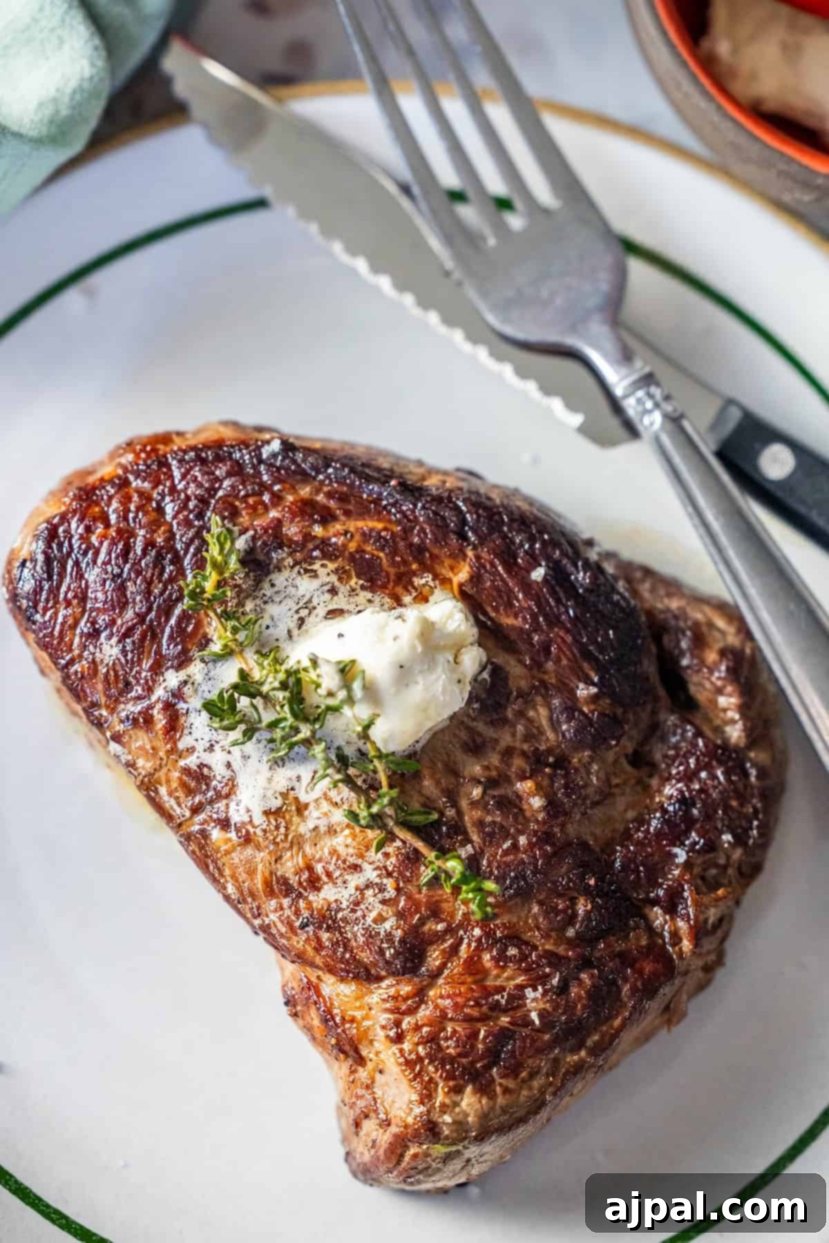 Cooked sirloin steak with butter and thyme on a plate.