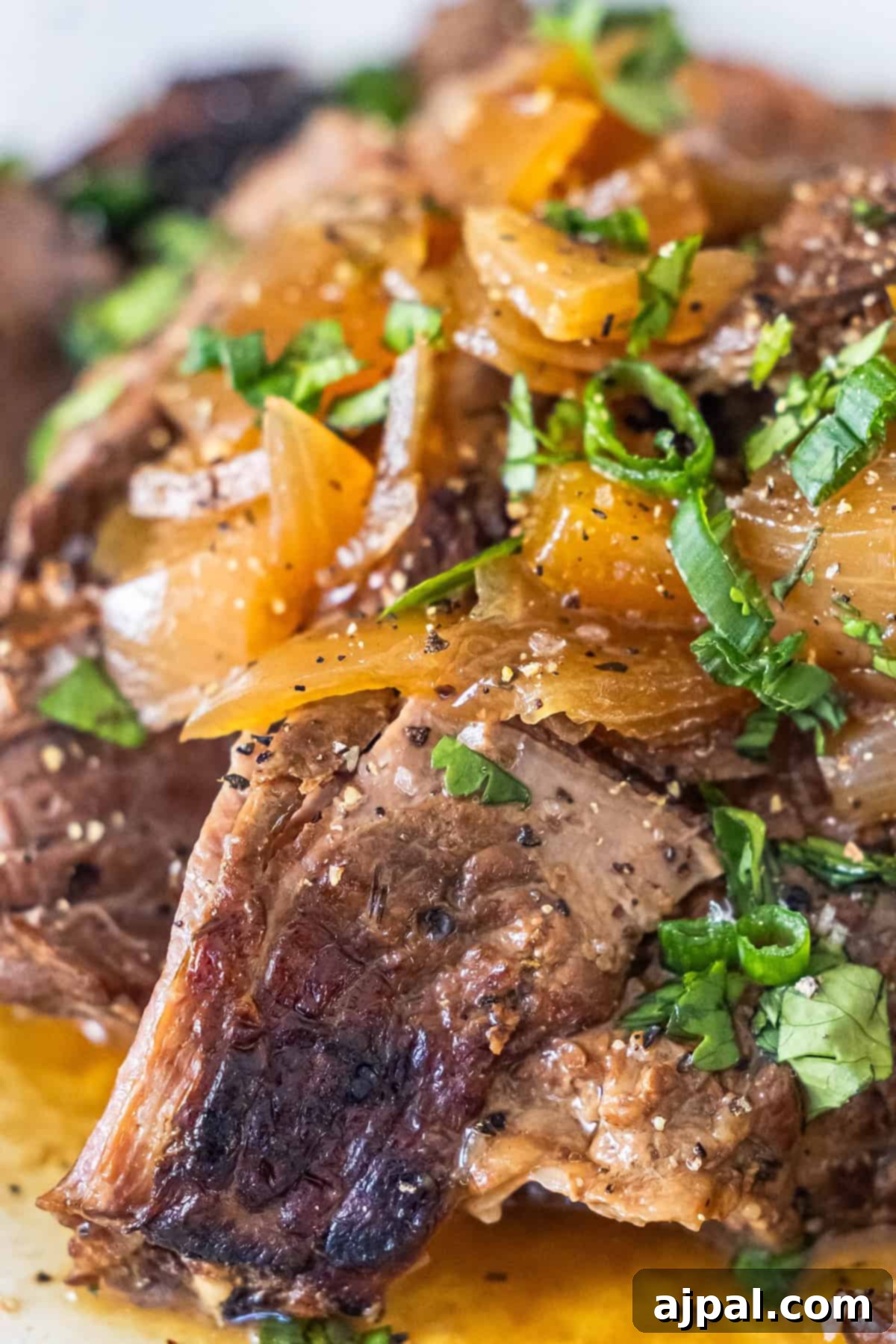 Close-up of cooked sirloin steak with onions and herbs.