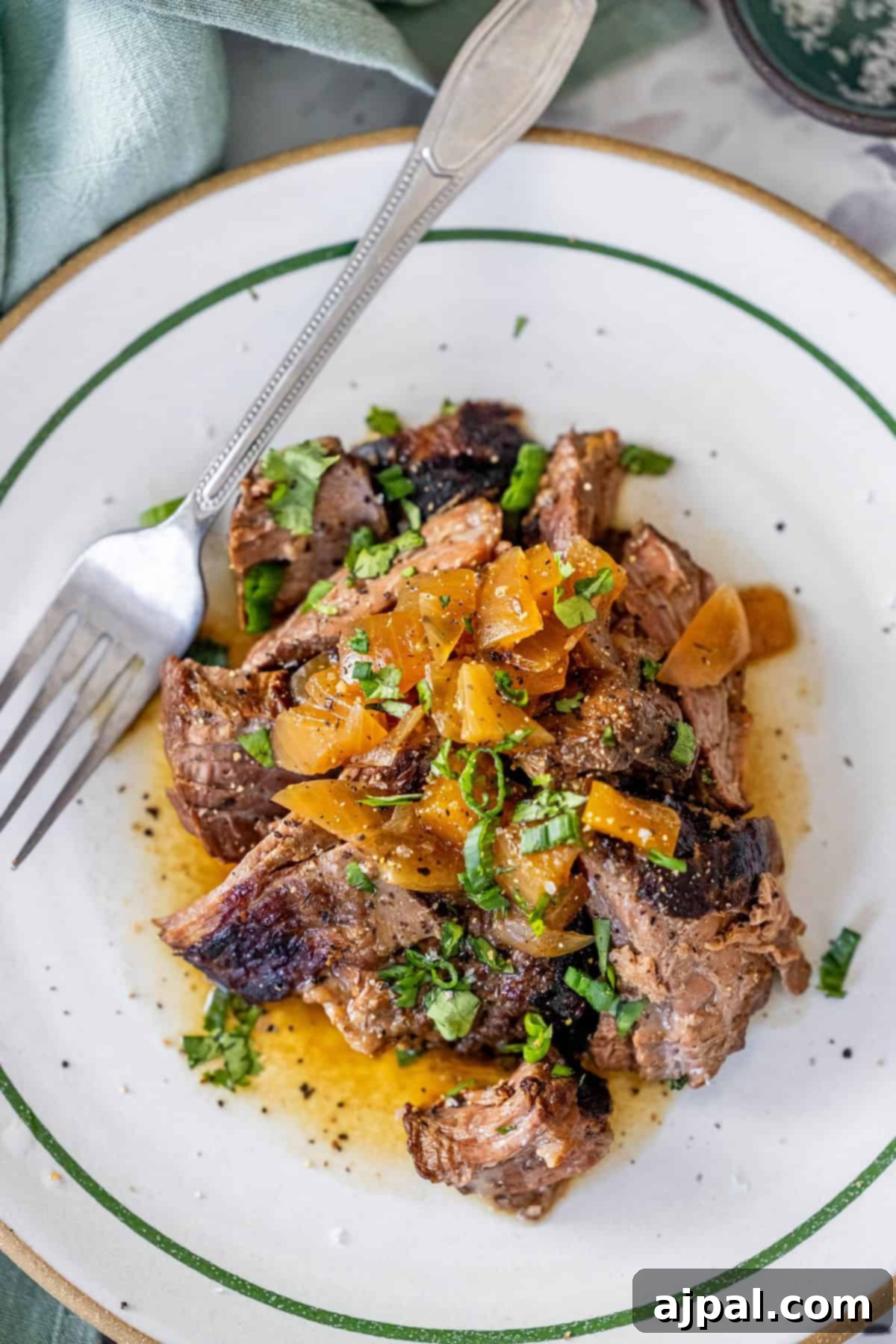 Sliced grilled steak topped with diced onions and herbs.