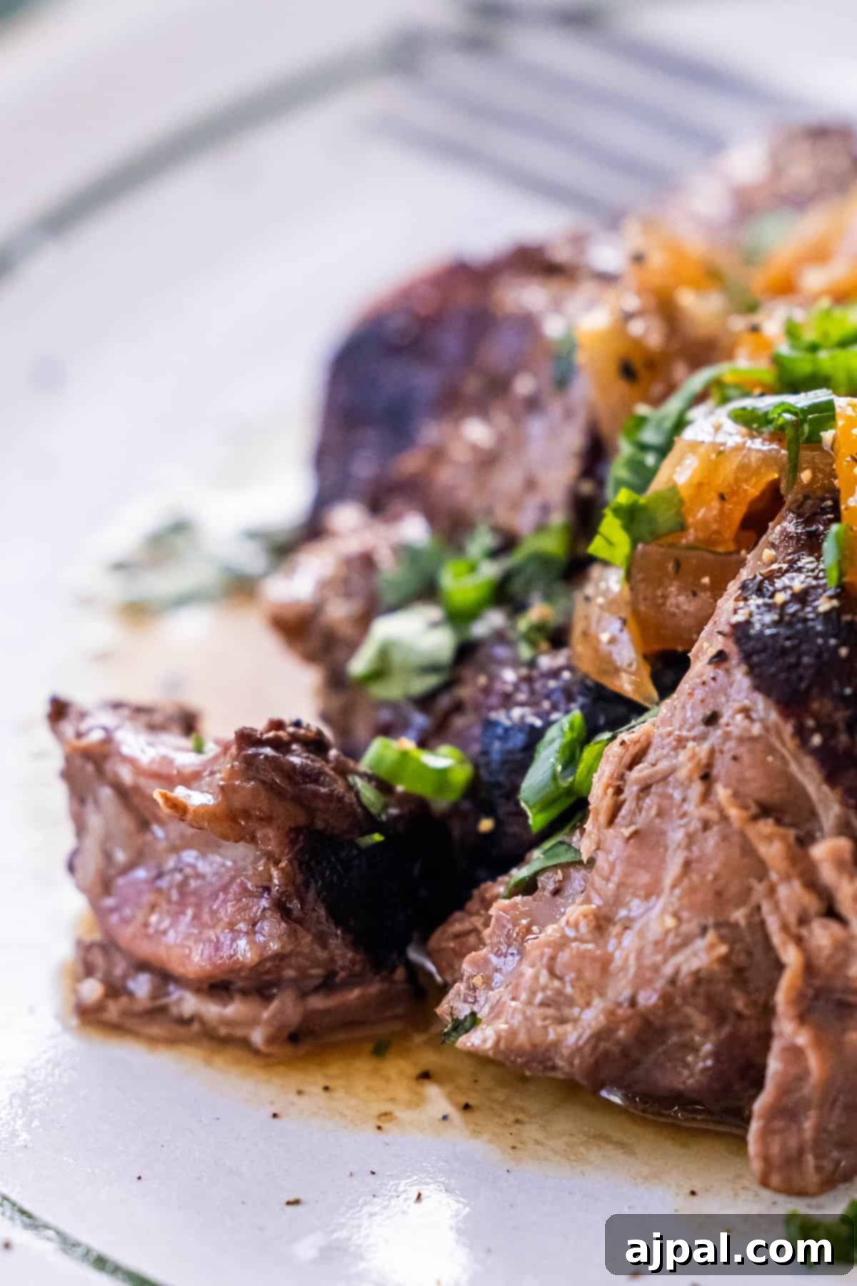 Close-up of tender slow cooker steak garnished with herbs and onions.