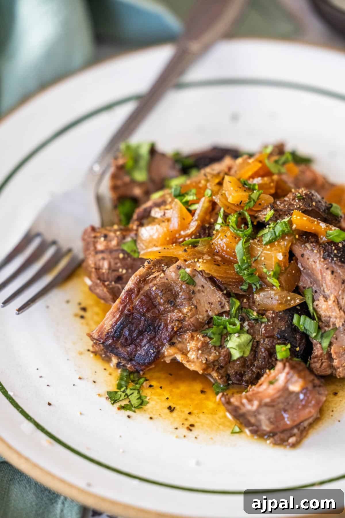 A plate of cooked beef topped with sautéed onions and herbs.