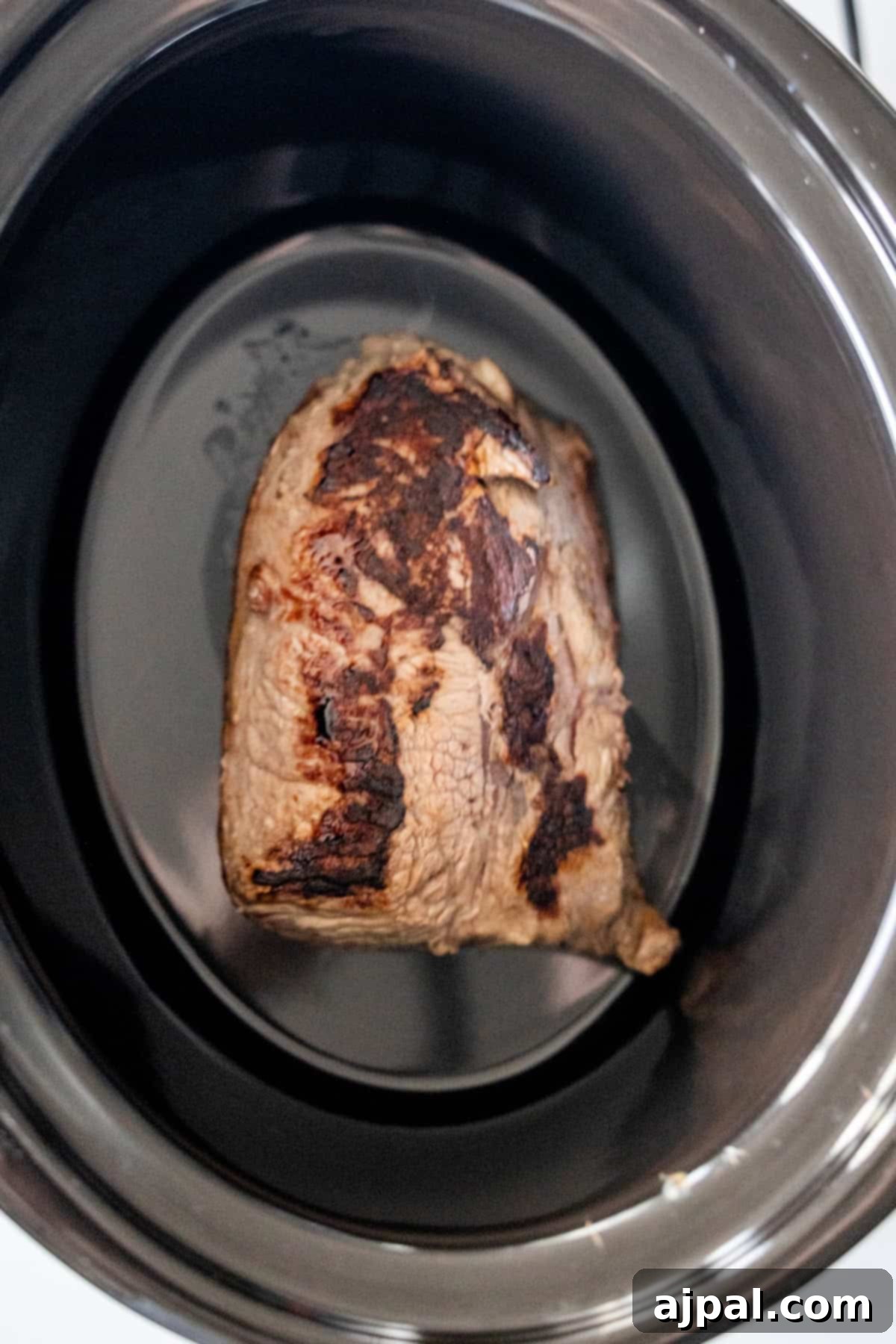 Seared Slow Cooker Sirloin Steak in the bottom of a slow cooker.