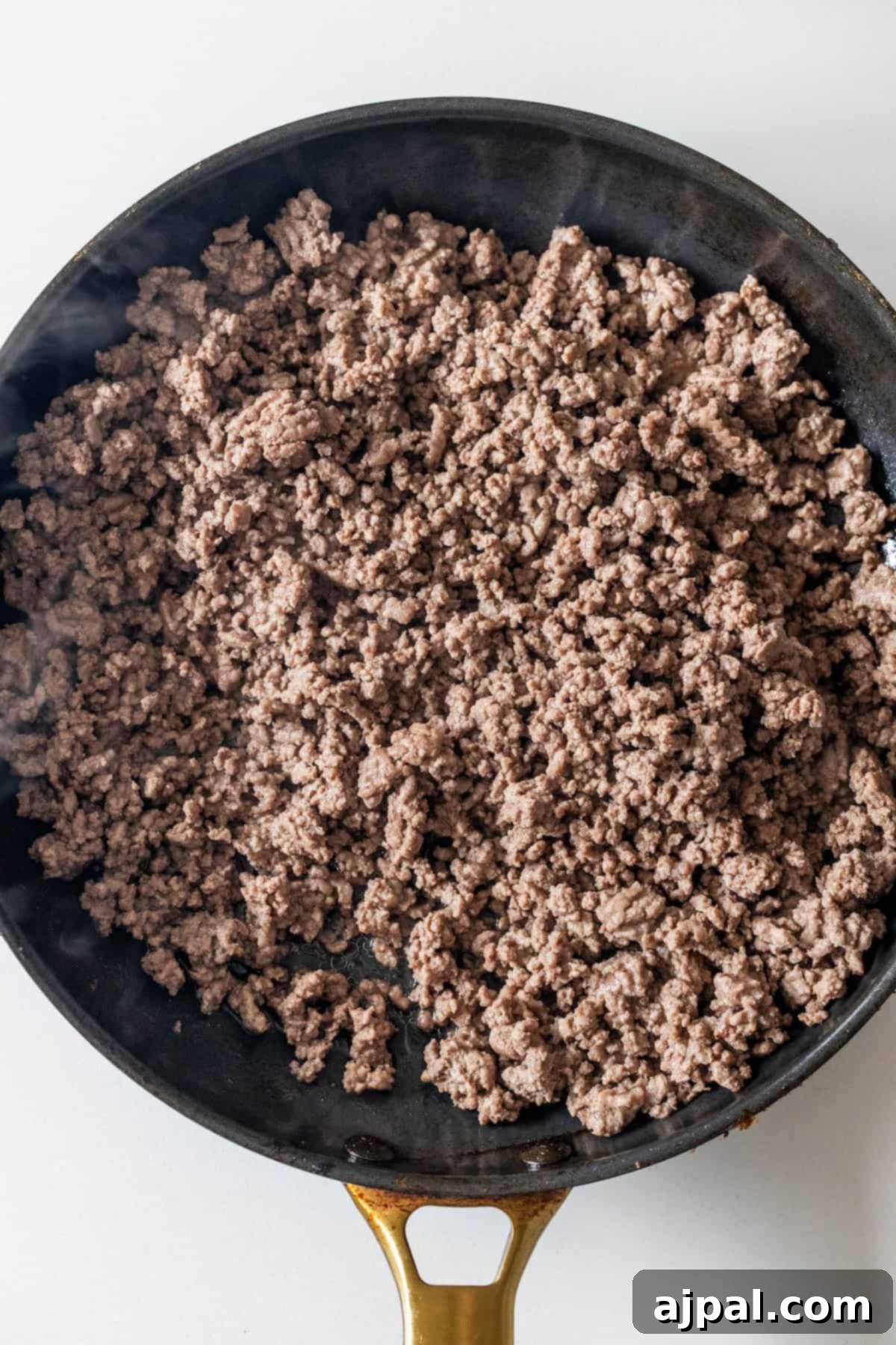 Cooked ground beef in a black skillet with a gold handle—perfect for starting your Dirty Rice Recipe.