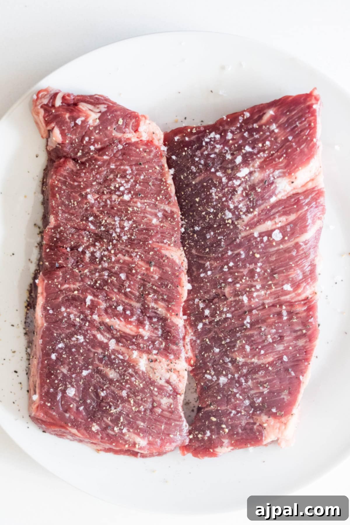 Raw Denver Steaks seasoned with salt and pepper