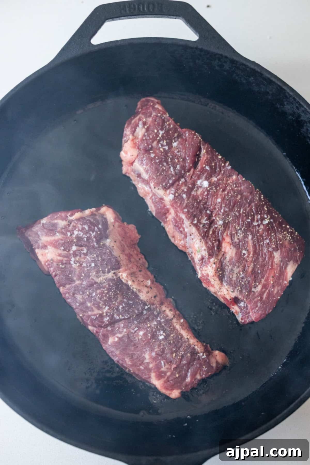 Denver Steaks searing in a hot cast iron skillet