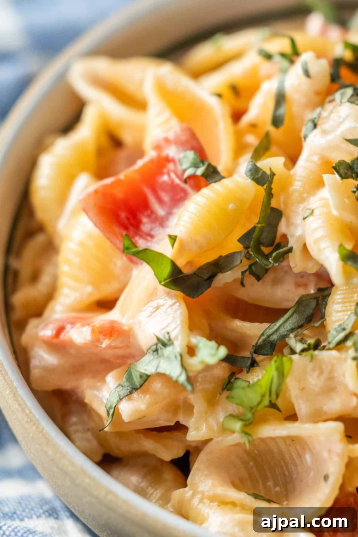Creamy Tomato Oricchiette Delight 3 Close-up of creamy pasta shells with diced tomatoes and herbs.