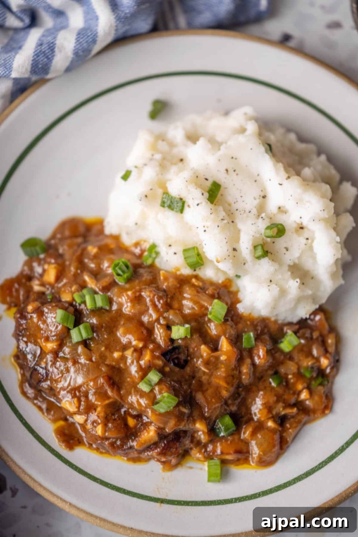 Country Steak in Gravy: A Hearty Homestyle Classic 3 Mashed potatoes and country steak with onion gravy on a plate.