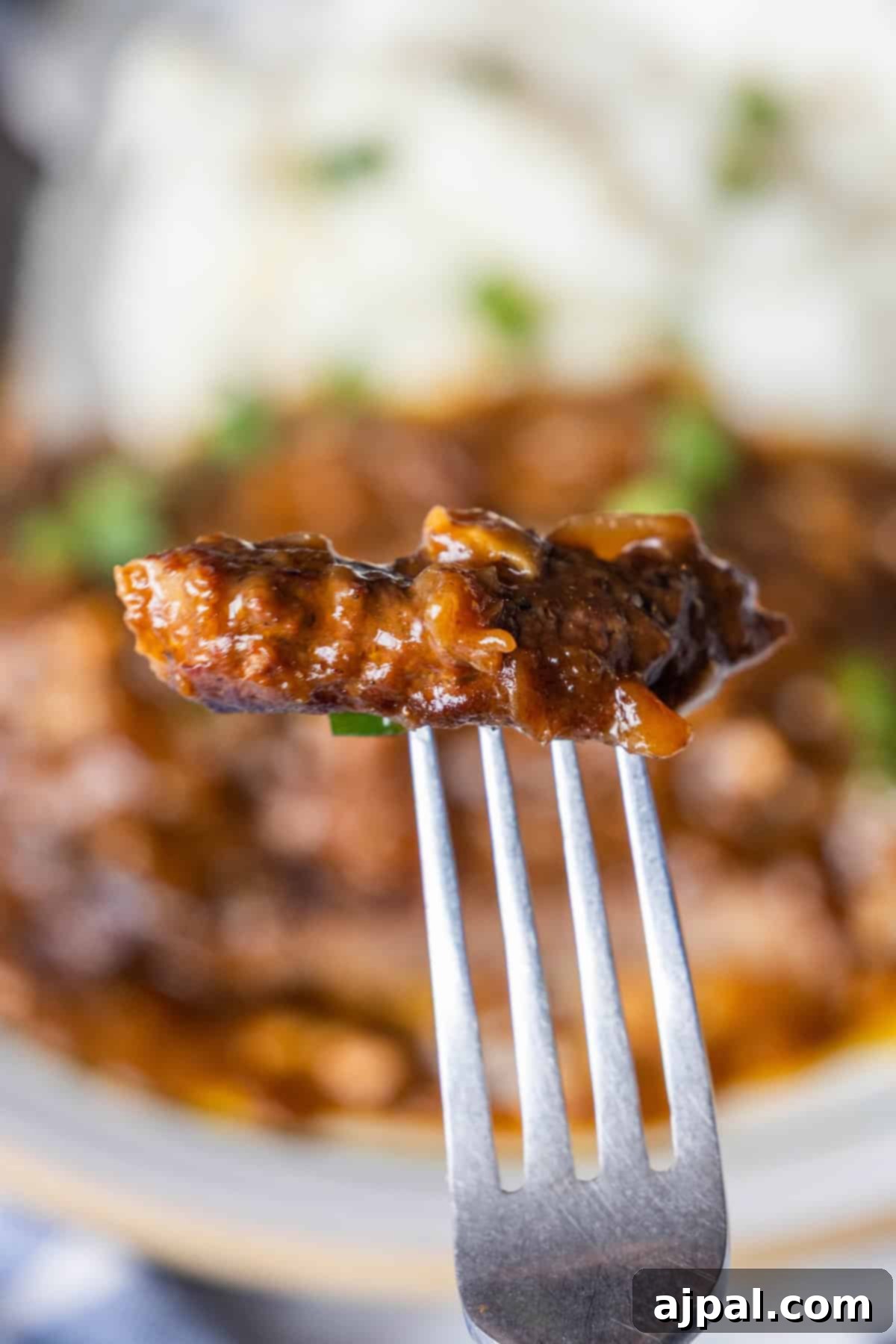 Country Steak in Gravy: A Hearty Homestyle Classic 4 Fork holding a piece of country steak with brown gravy.
