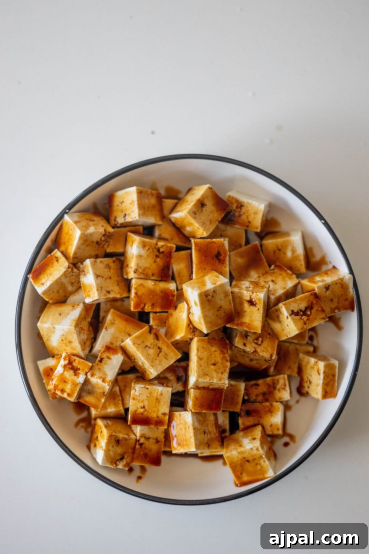 Tofu cubes marinating in a bowl of sauce.