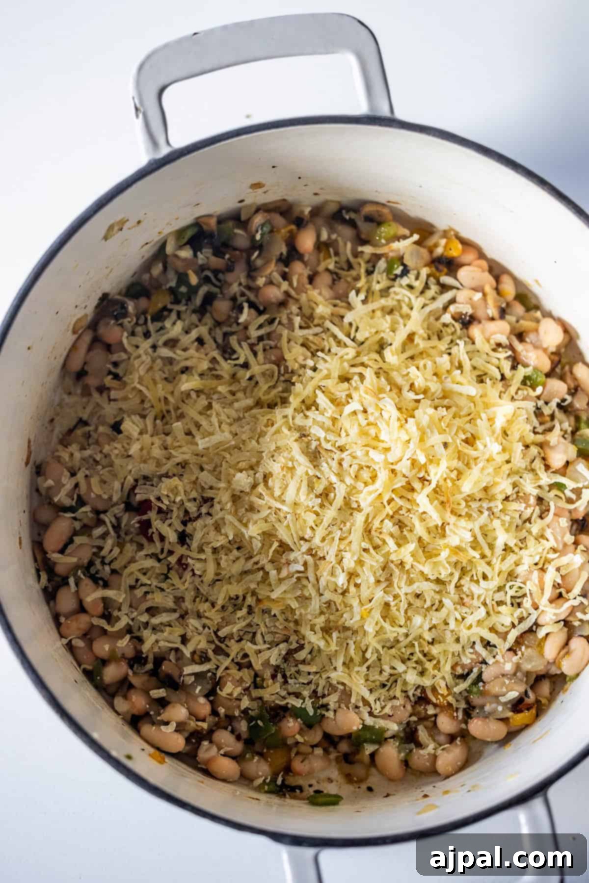 Vegan Crispy Potato Soup 10 Shredded cheese on top of vegetables in a pot.