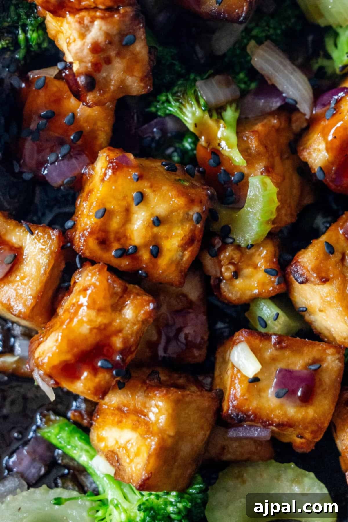 Sizzling Tofu Stir-Fry 2 Close-up of Tofu Stir Fry with crispy tofu, sesame seeds, broccoli, celery, and red onion in a savory sauce.