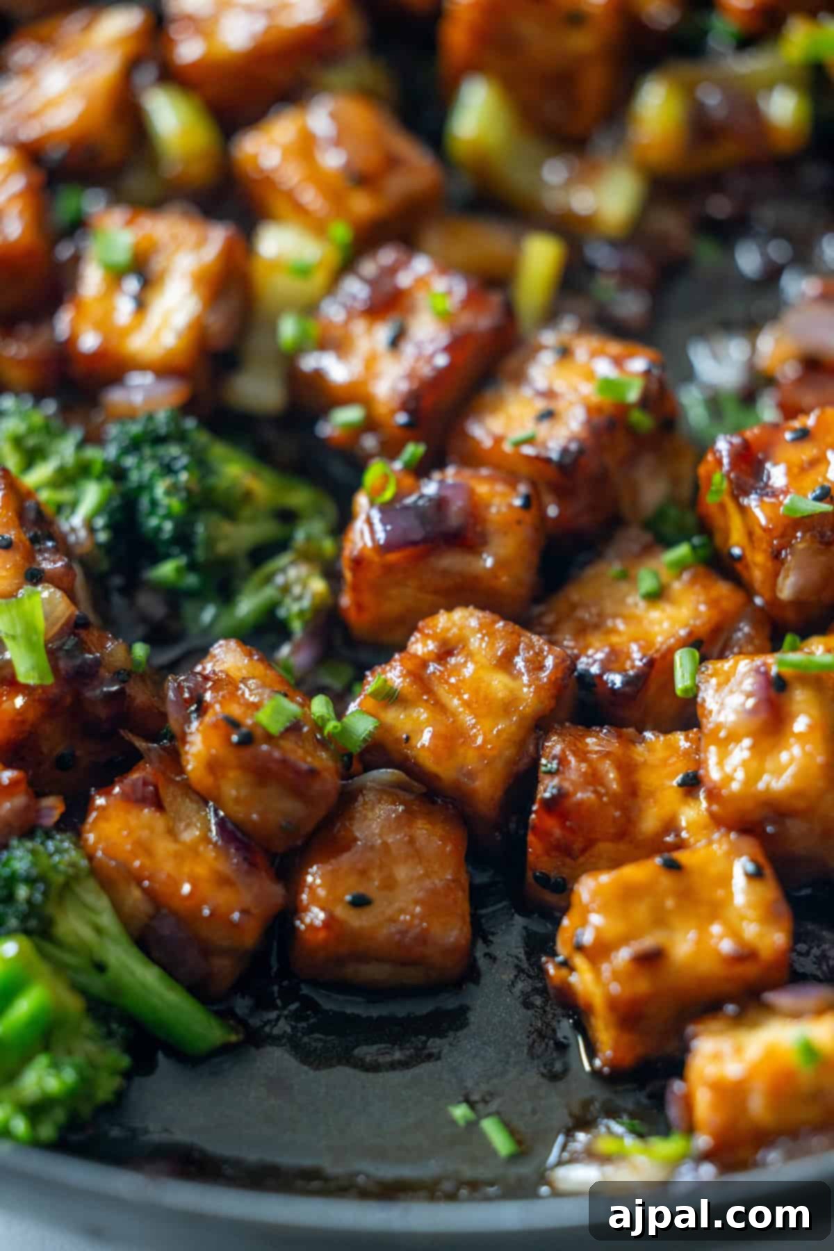 Sizzling Tofu Stir-Fry 3 Tofu and broccoli cooking in a skillet for a tofu stir fry, garnished with chives.